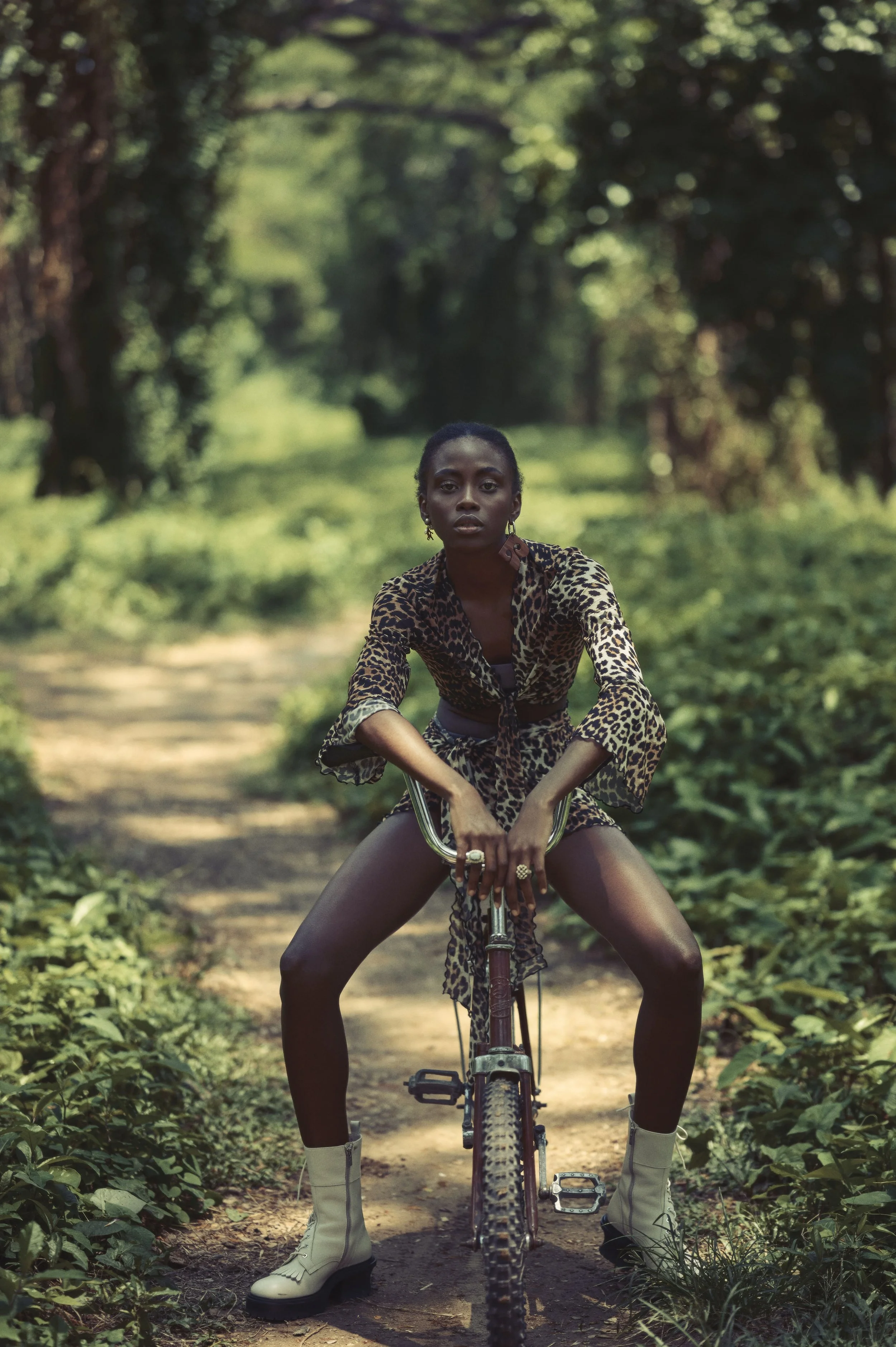 Een vrouw in een dierenprint outfit op een bospaadje zittend op een fiets gefotografeerd door Eric van den Elsen ergens in Cuba.