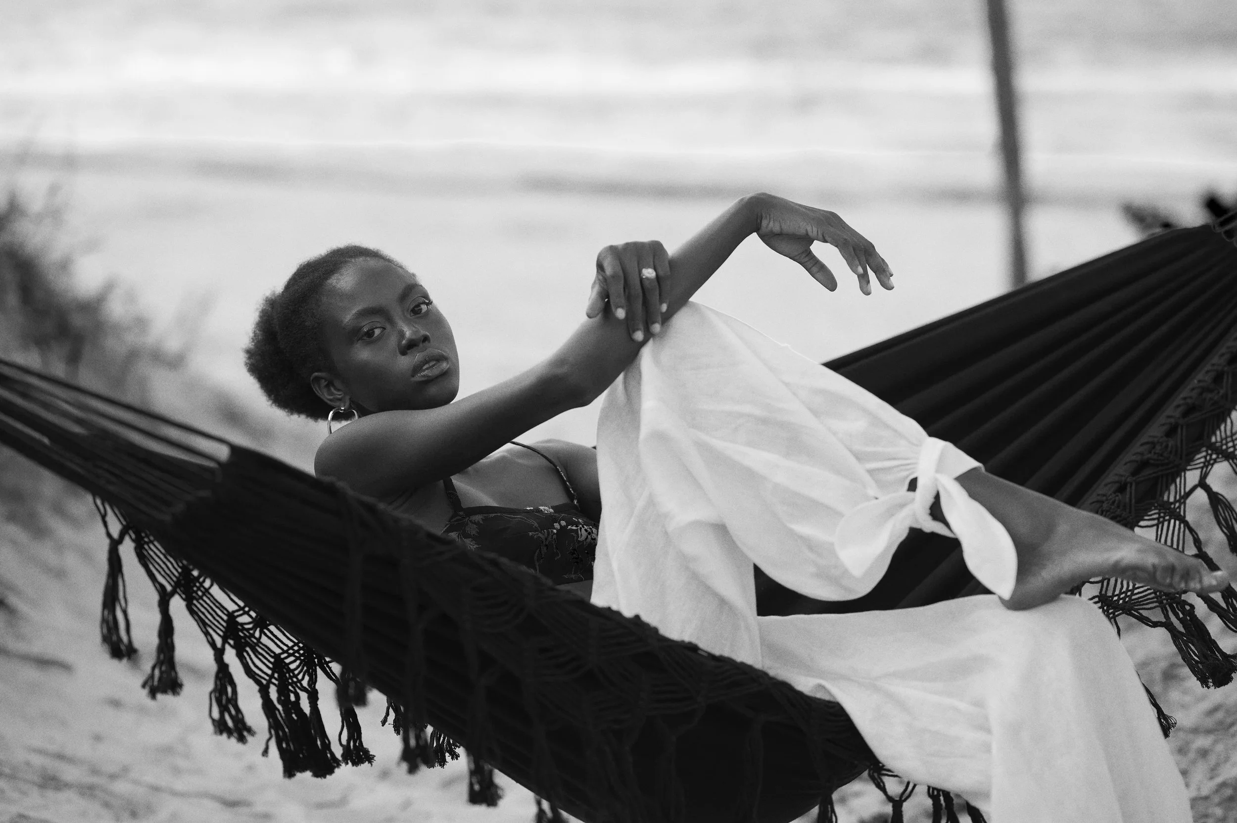 Een zwart-wit foto van een vrouw liggend op een gerechtigde hangmat, met een relaxte houding en een serieuze blik gefotografeerd door Eric van den Elsen.