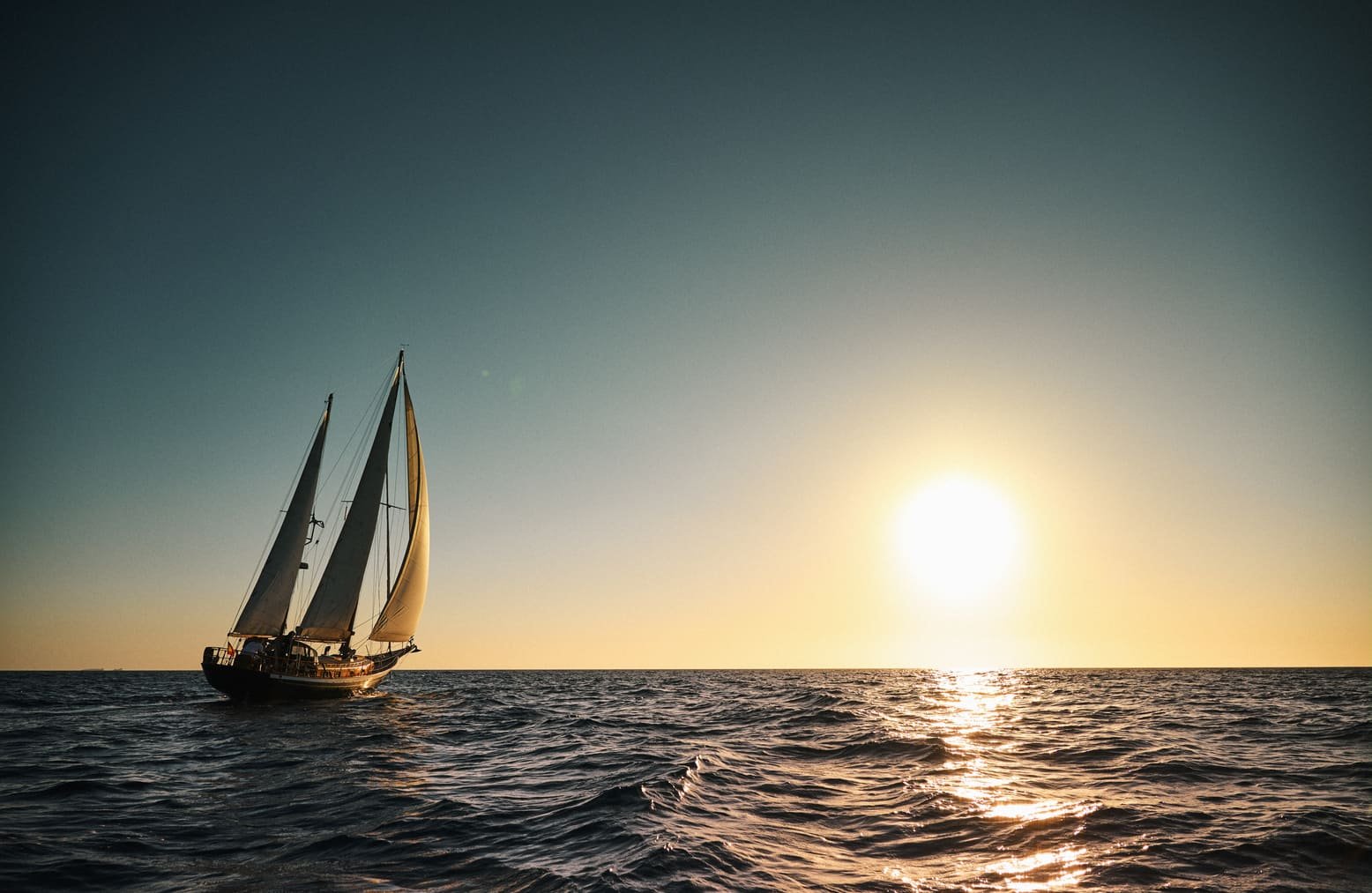 Een zeilboot op de oceaan tijdens zonsondergang.