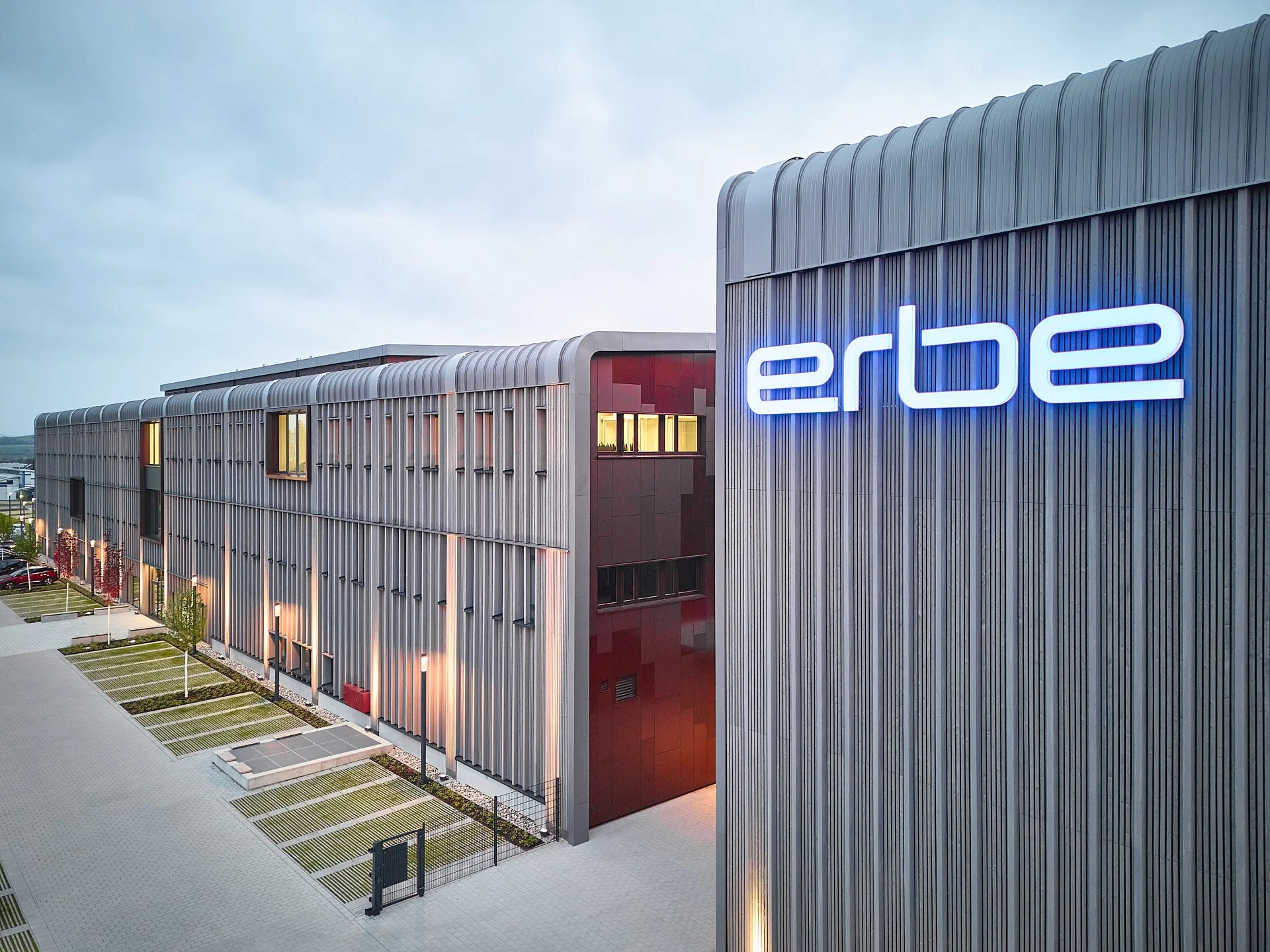 Erbe 4.i Industriearchitektur zur blauen Stunde mit beleuchteten Innenräumen und roter Fassade