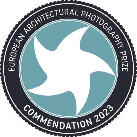 Logo des Europäischen Architekturfotografie-Preises 2023 mit Auszeichnung, zeigt ein stilisiertes Windrad auf blauem Hintergrund.