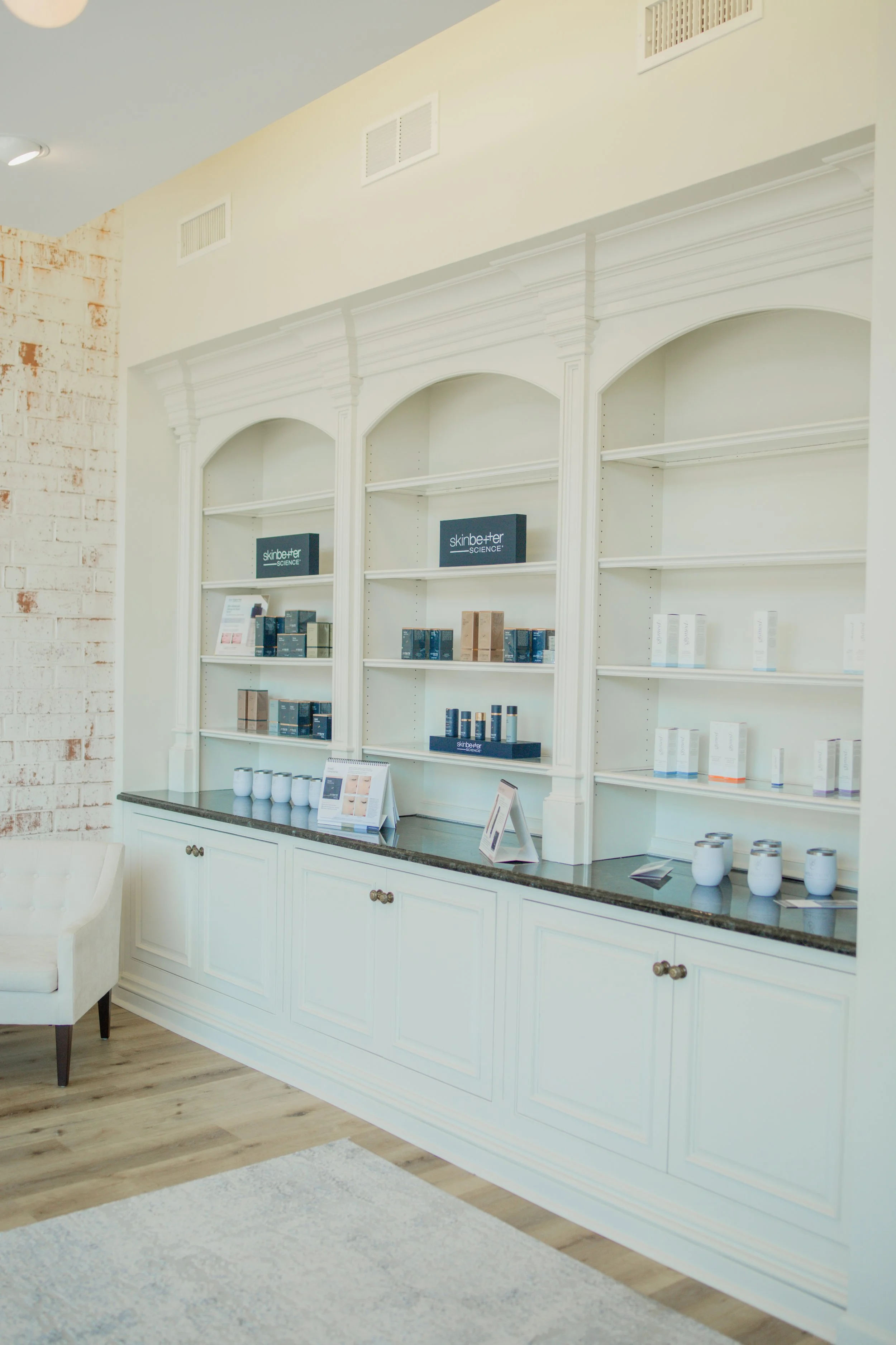 Shelves displaying skincare products and pamphlets in a bright room with a white cabinet.