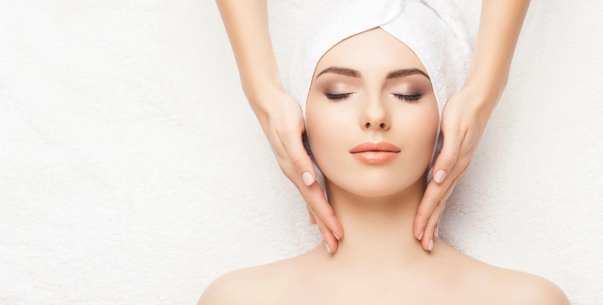 Woman receiving a face massage with a towel on her head.