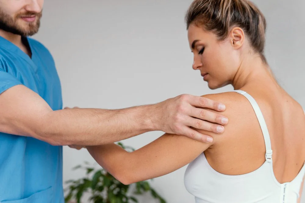 A healthcare professional examining a woman's shoulder during a medical consultation.