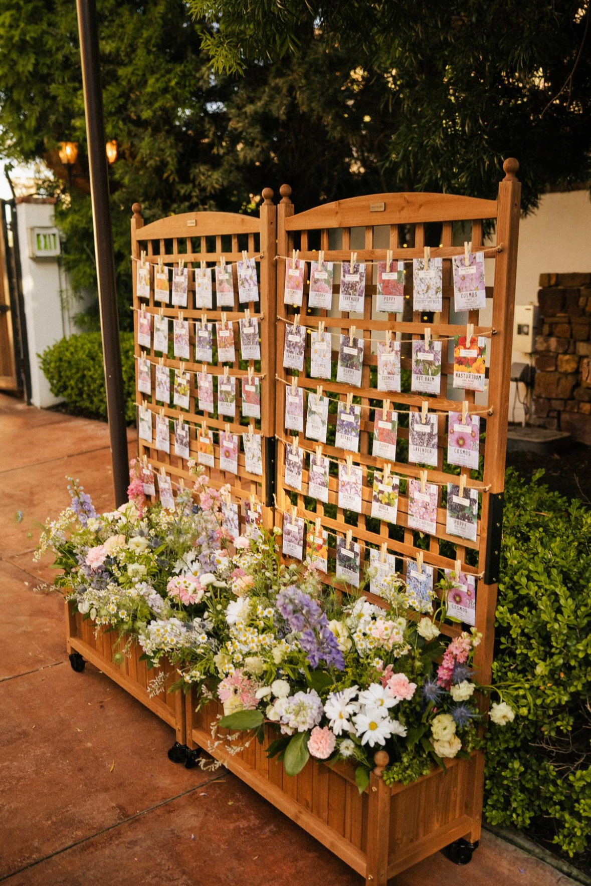 Trellis and flower boxes being used as a seating chart with wildflowers filling the trellis box and seed packets being used for the seating chart