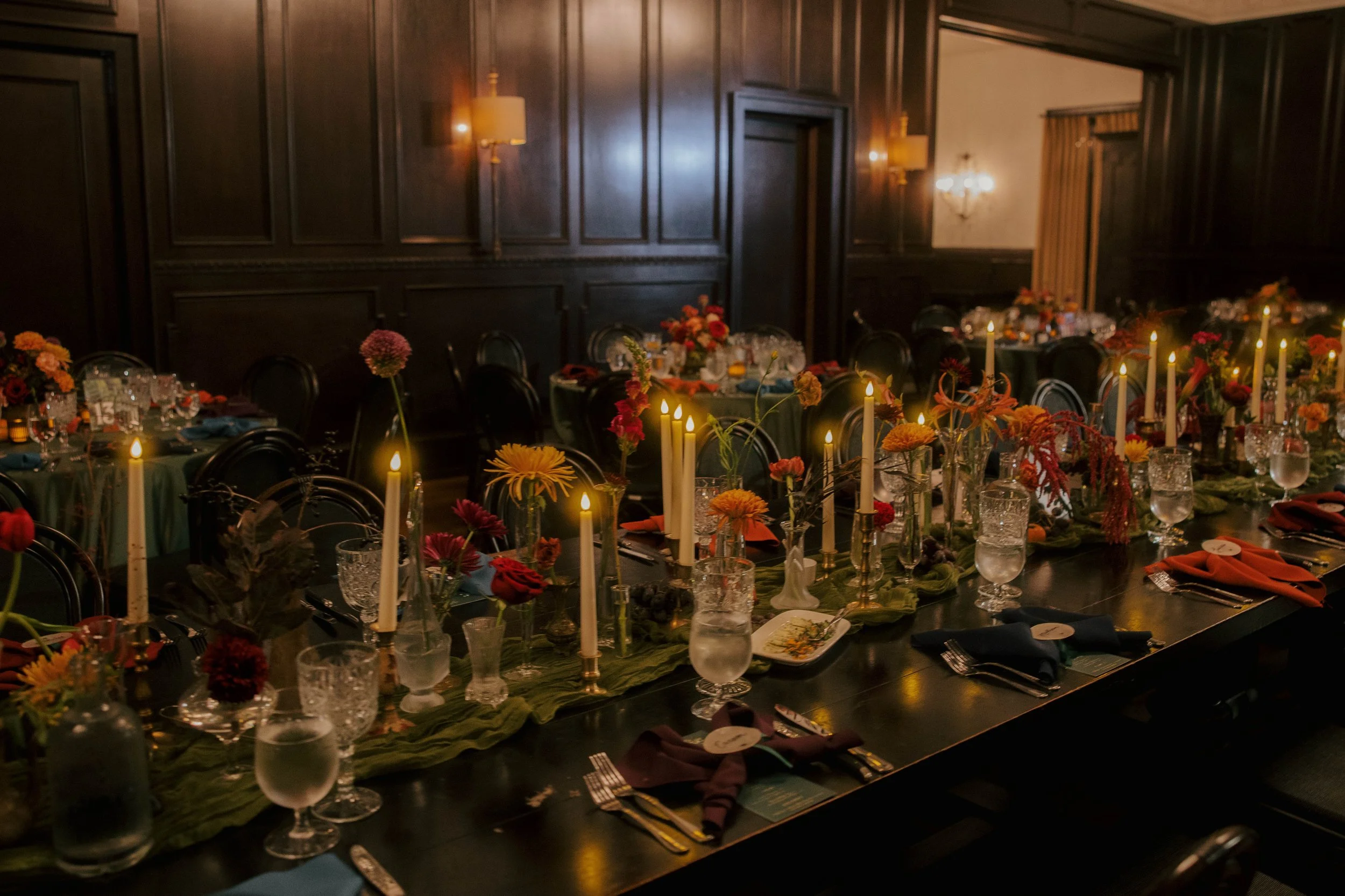 long rectangular table with candlelight, brass bud vases, and jewel toned flowers