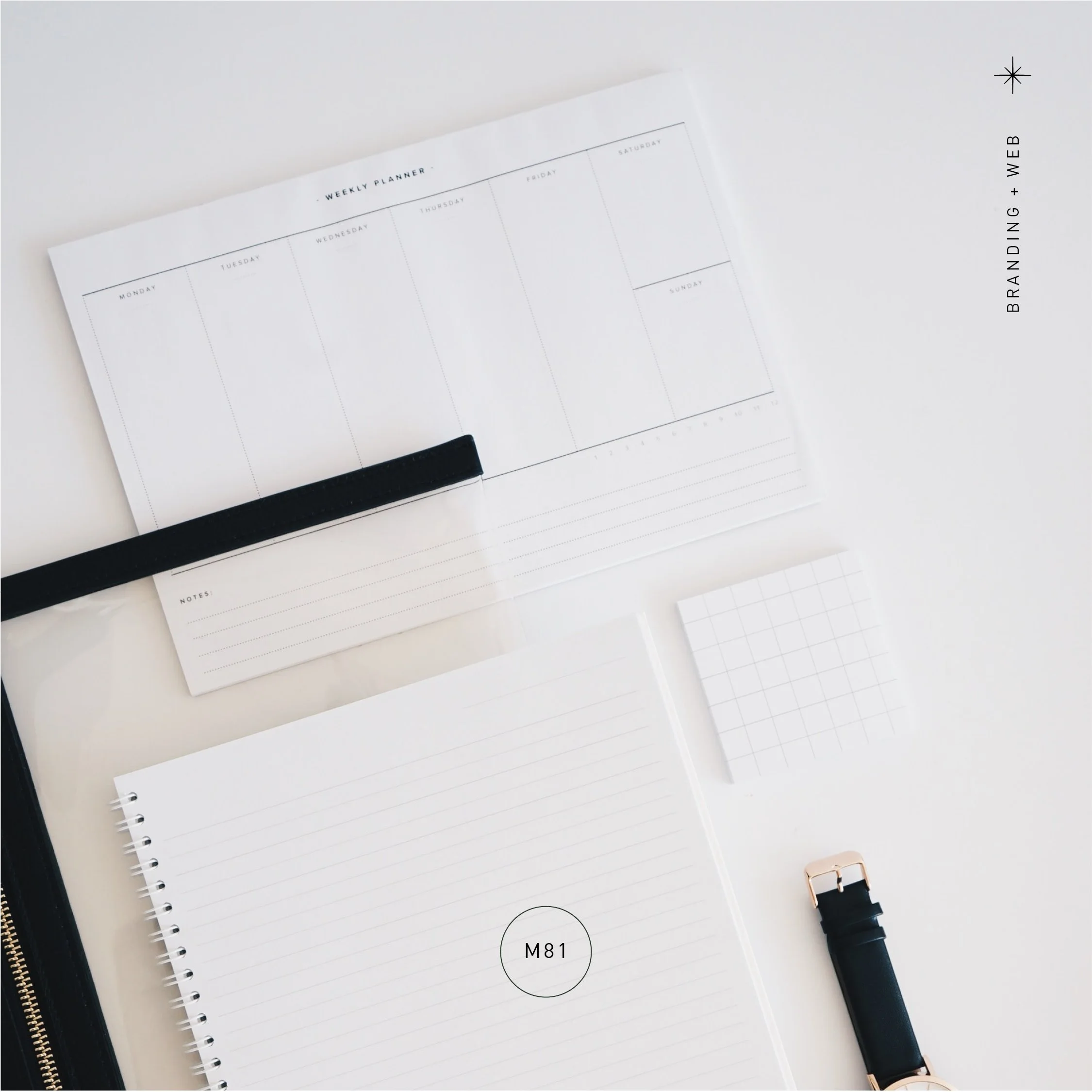 A flat lay of stationery items on a white surface, including a weekly planner, lined notebook, small grid paper, a black strap, and a black watch with a rose gold buckle.