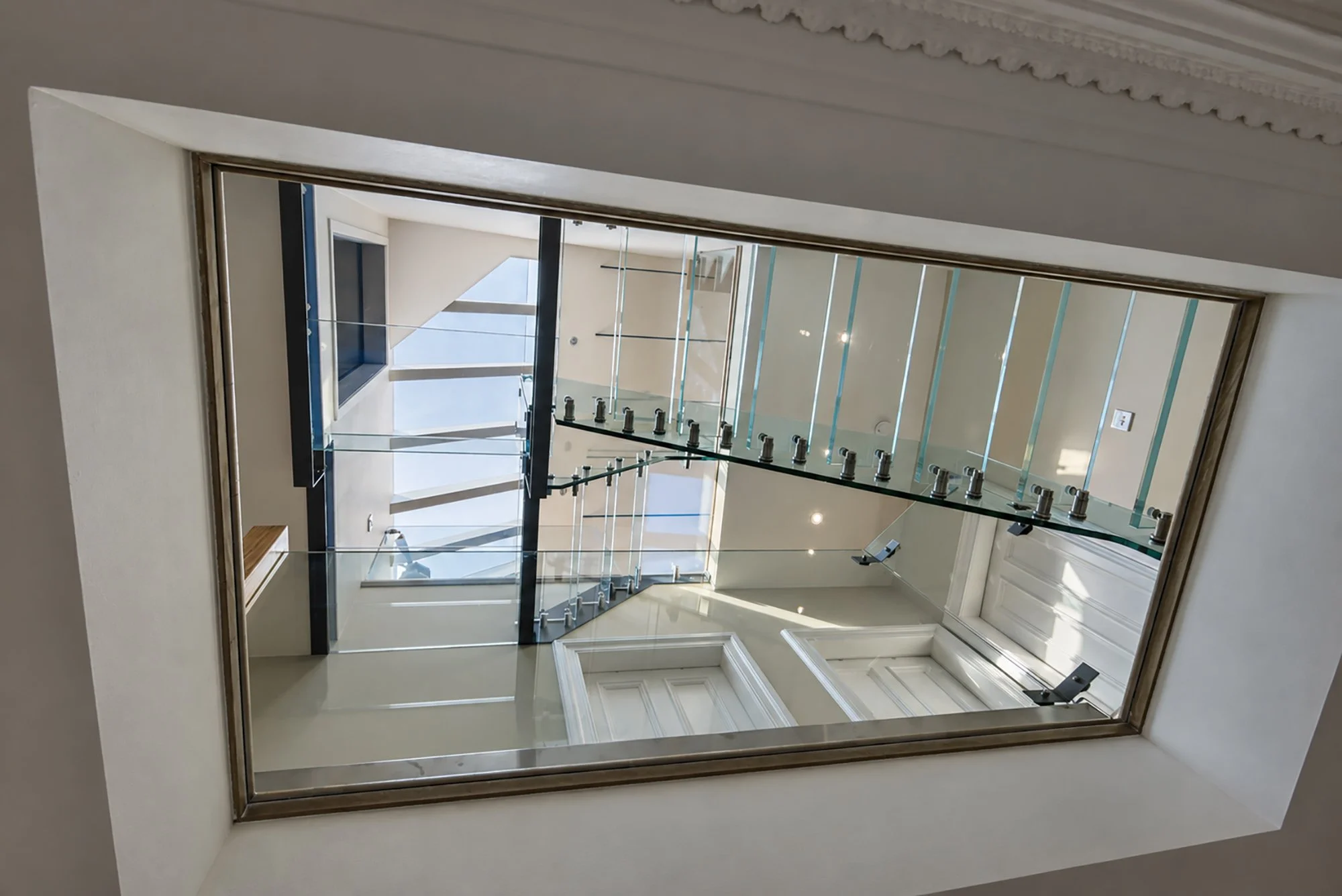 View upwards through the glass floor and layered glazed staircase of a Newport-on-Tay loft conversion.
