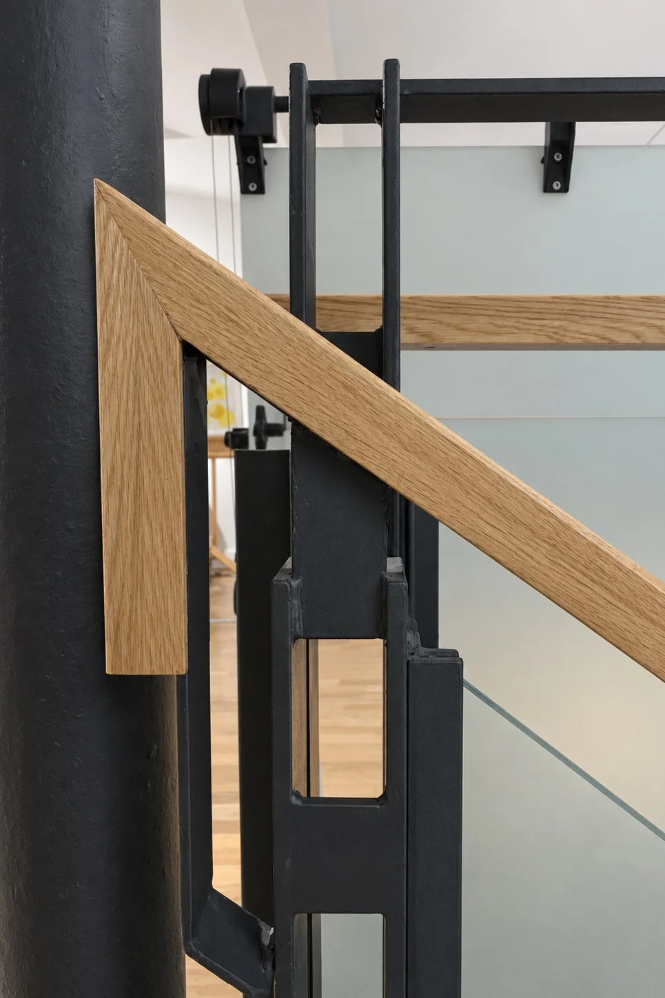Detail of the bespoke oak handrail, black steel balustrade and frosted glass panels.