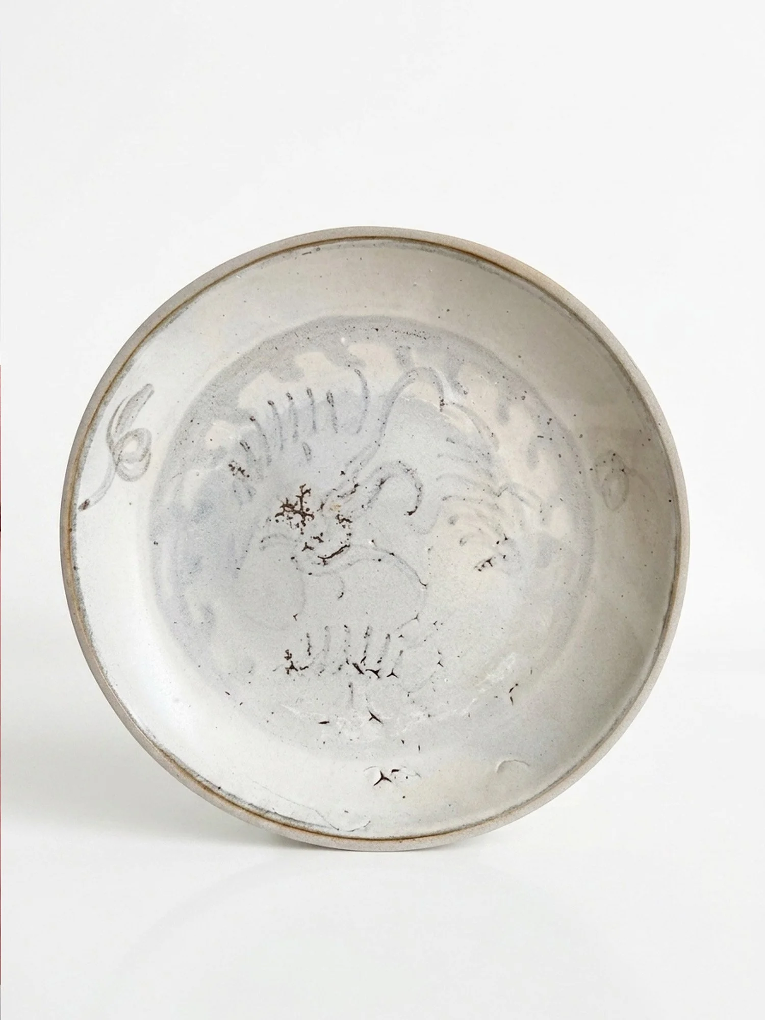 Overhead interior view of a 19th-century Qing Dynasty Tek Sing shipwreck porcelain dish with underglaze blue floral motif.