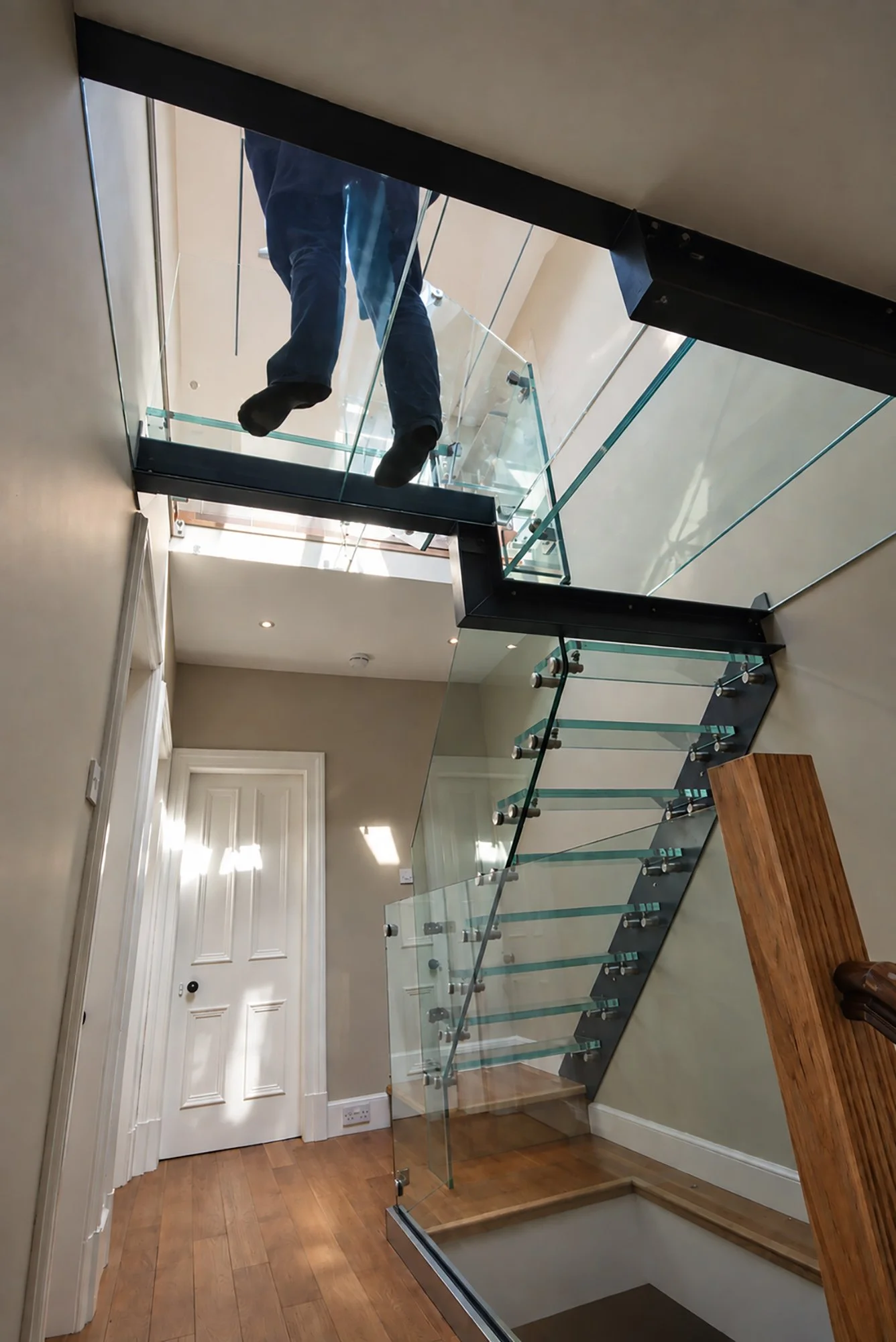 Person walking across a transparent glass floor above the bespoke glass staircase in a Newport-on-Tay loft conversion.