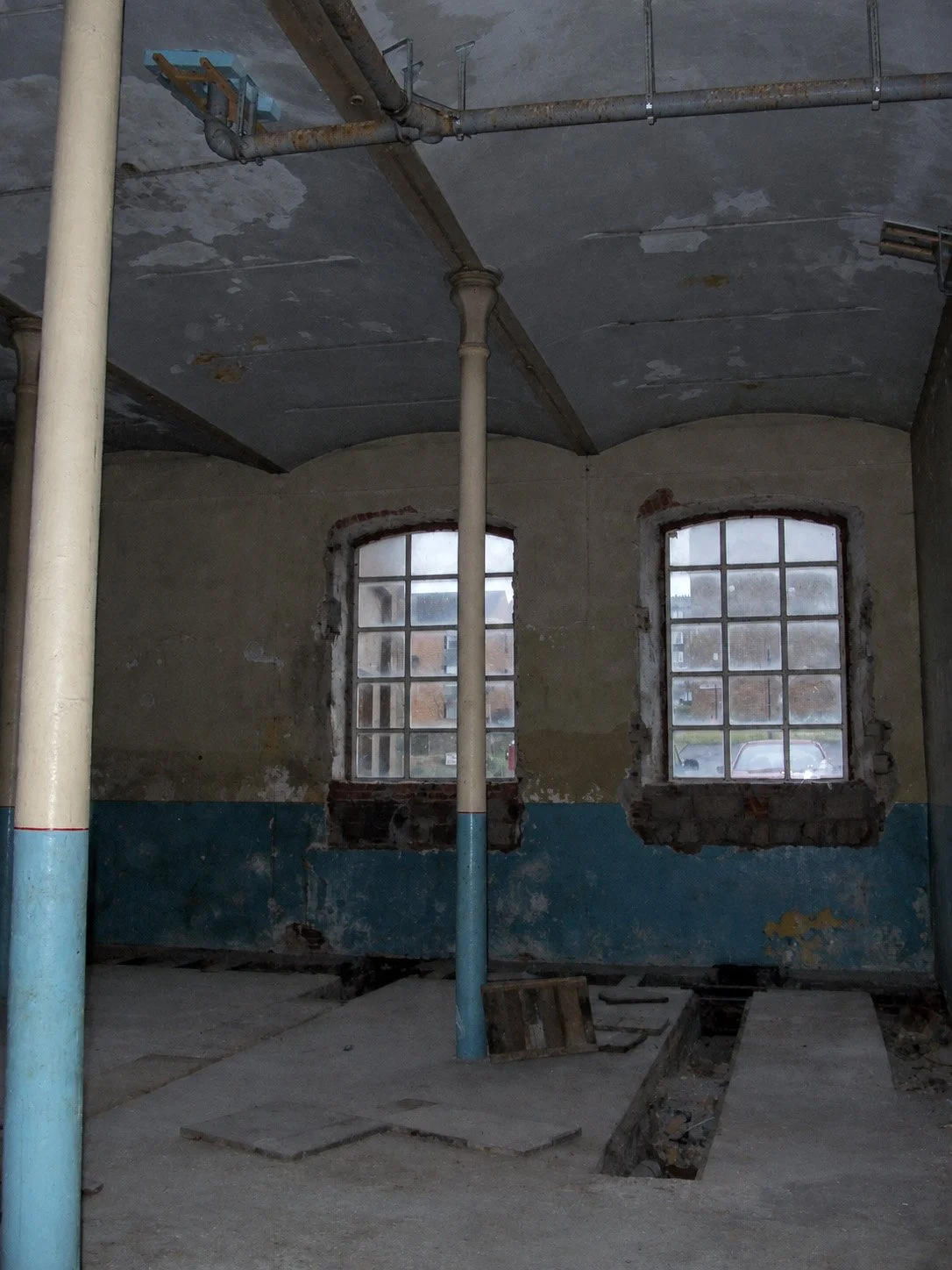 Derelict engine room before conversion, showing the original industrial windows, columns and floor channels.