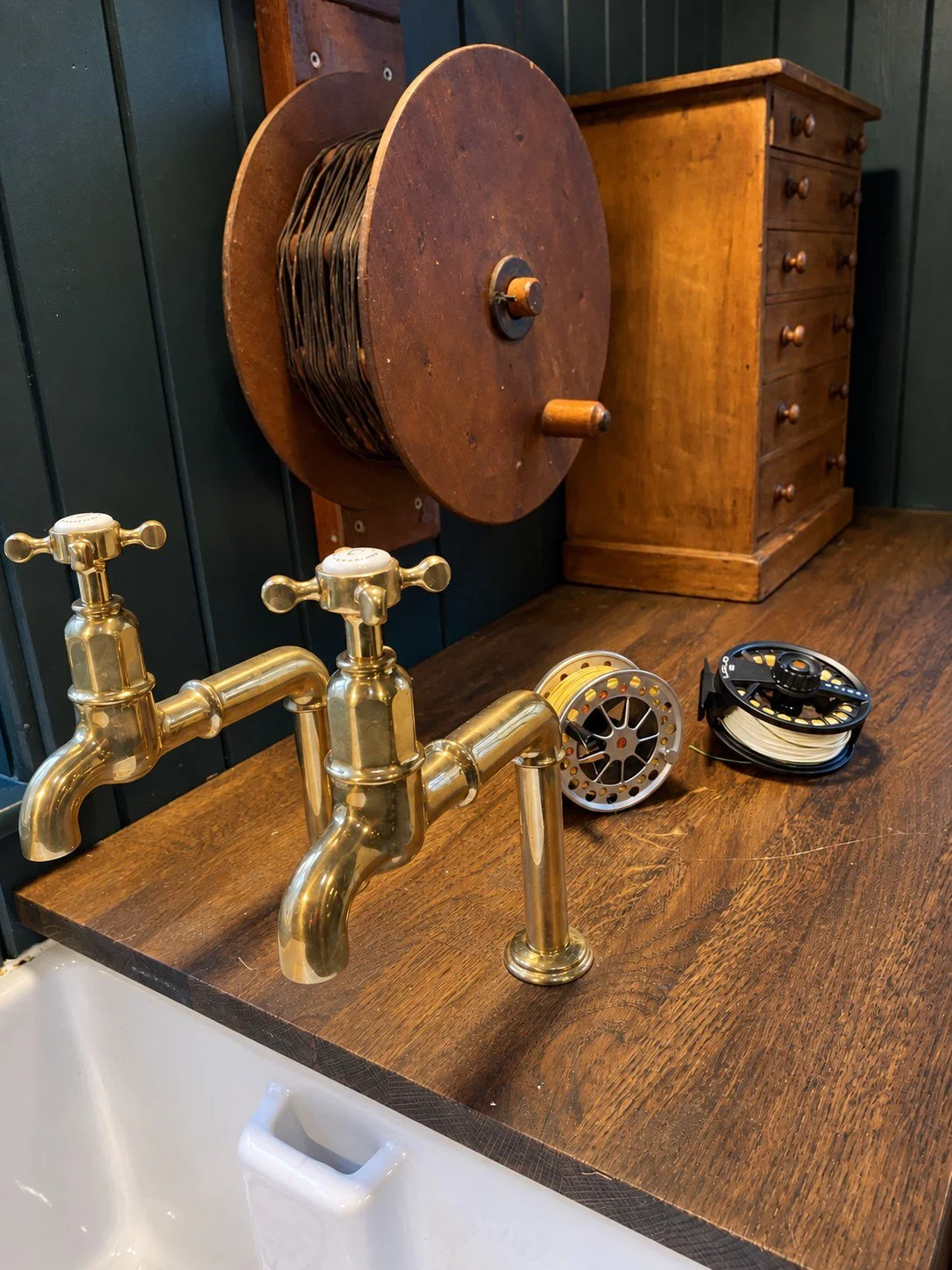 Brass taps and fishing reels on an aged timber worktop in an Aberdeenshire rod room.