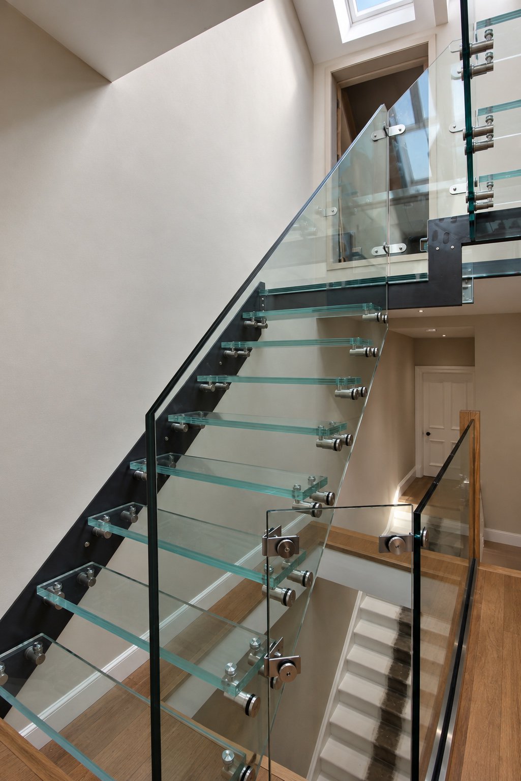 Bespoke glass staircase with cantilevered glass treads, frameless balustrades and a black steel structure in a Newport-on-Tay loft conversion.