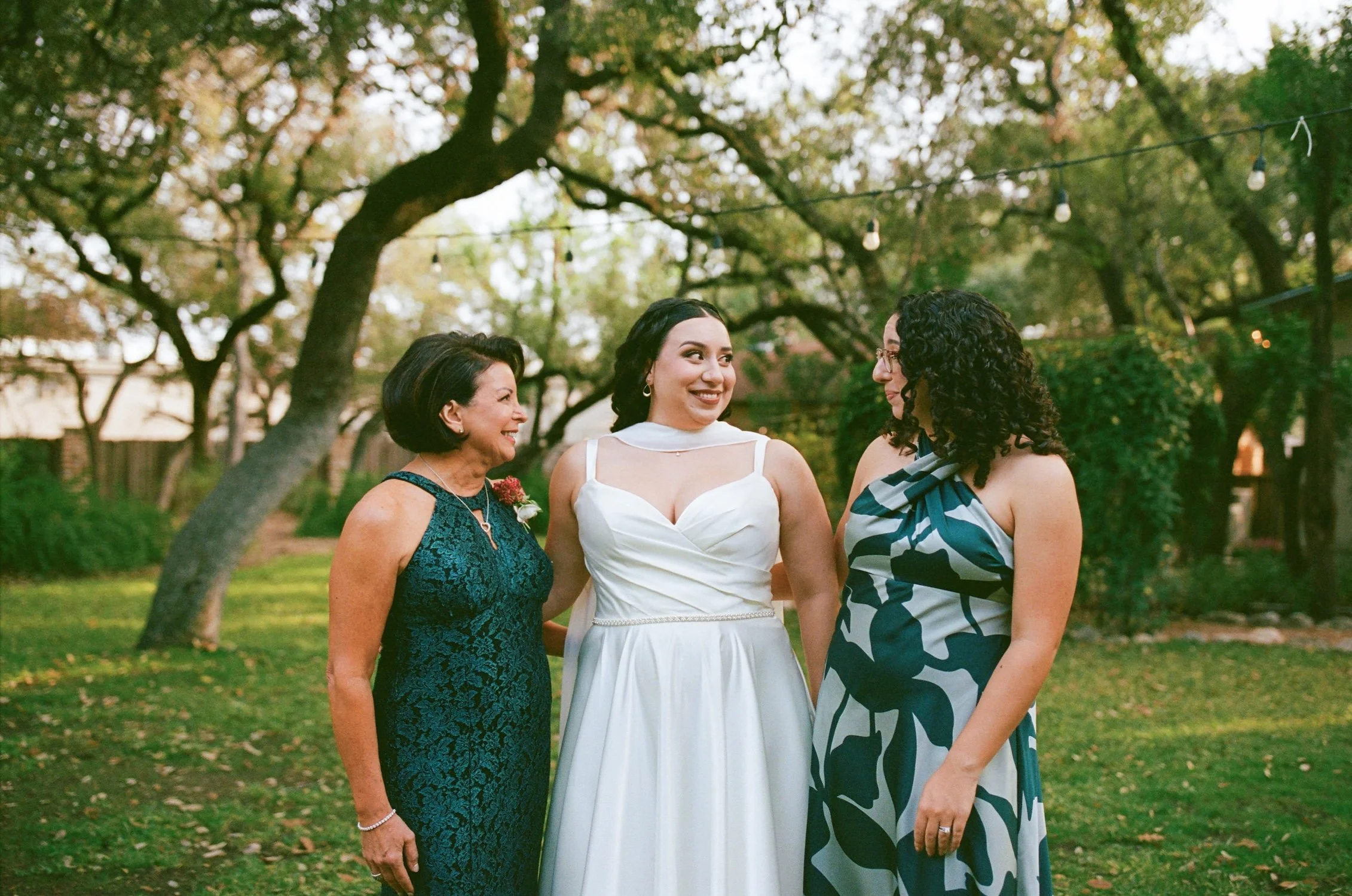 Texas bride has her arms around two female family members and looks to the one on the left with an excited smile.