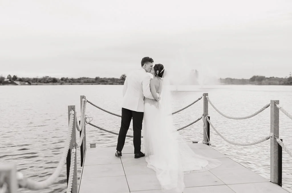 Intimate black-and-white wedding portrait on the lake boardwalk at The Red Berry Estate in San Antonio.
