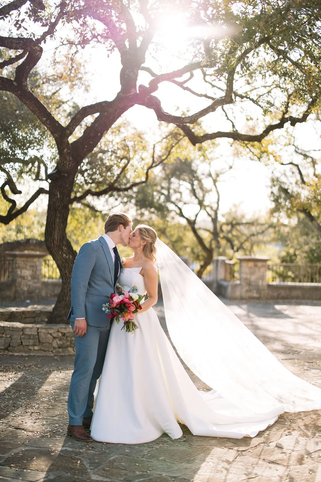Just married couple kisses beneath the oak trees at Lost Mission, a scenic San Antonio wedding venue known for its Hill Country views and timeless charm.