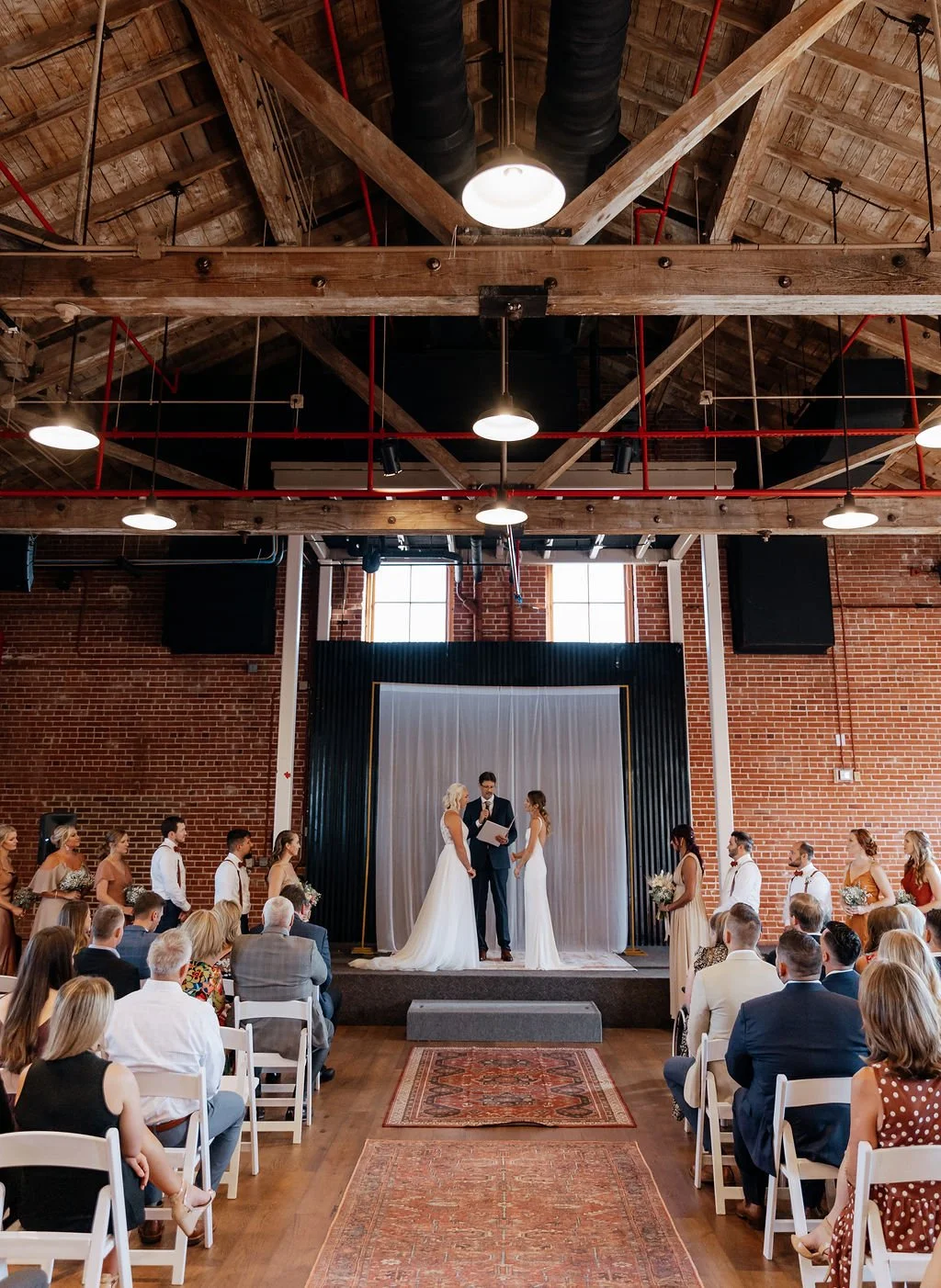 Wedding ceremony inside The Espee’s restored event space, a San Antonio wedding venue with exposed brick, industrial beams, and warm lighting.