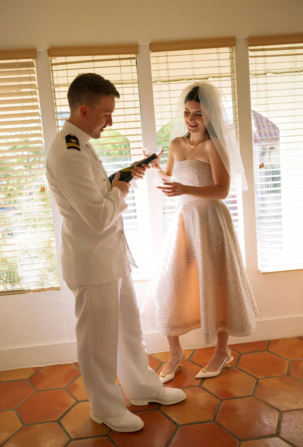 Couple laughing while opening champagne together inside Austin Motel suite