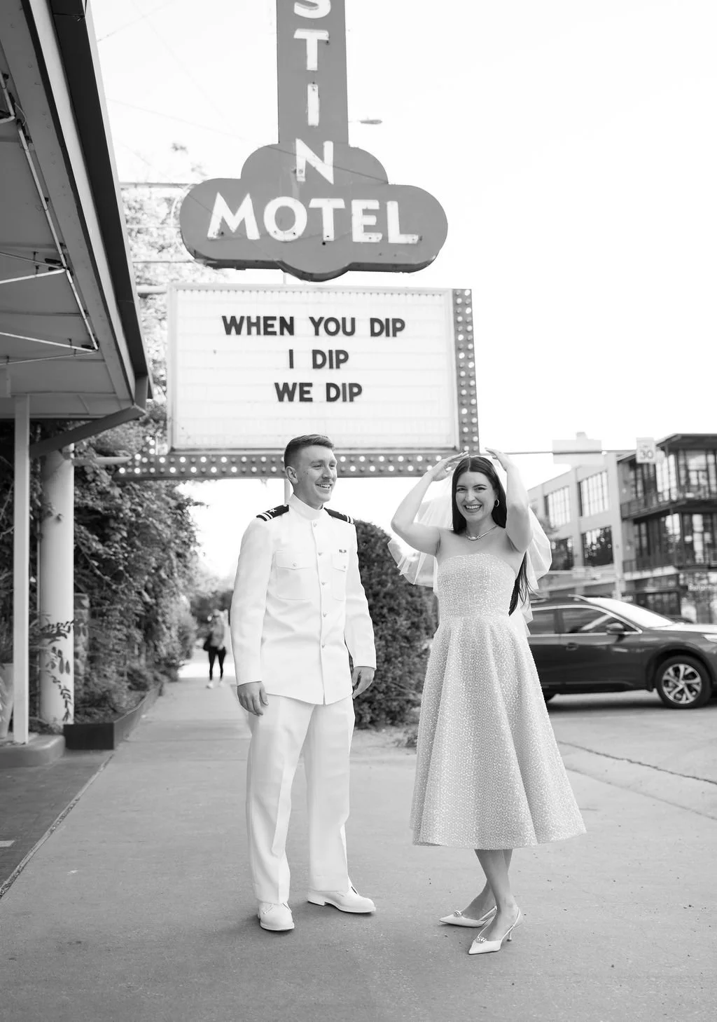 Black and white photo of couple walking together under Austin Motel marquee