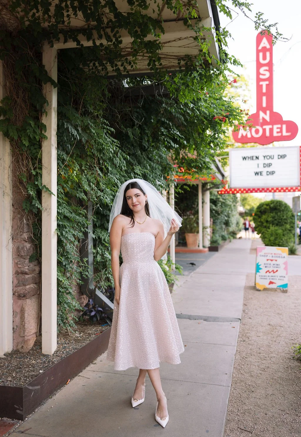 Stephanie standing and smiling outside Austin Motel with marquee in background