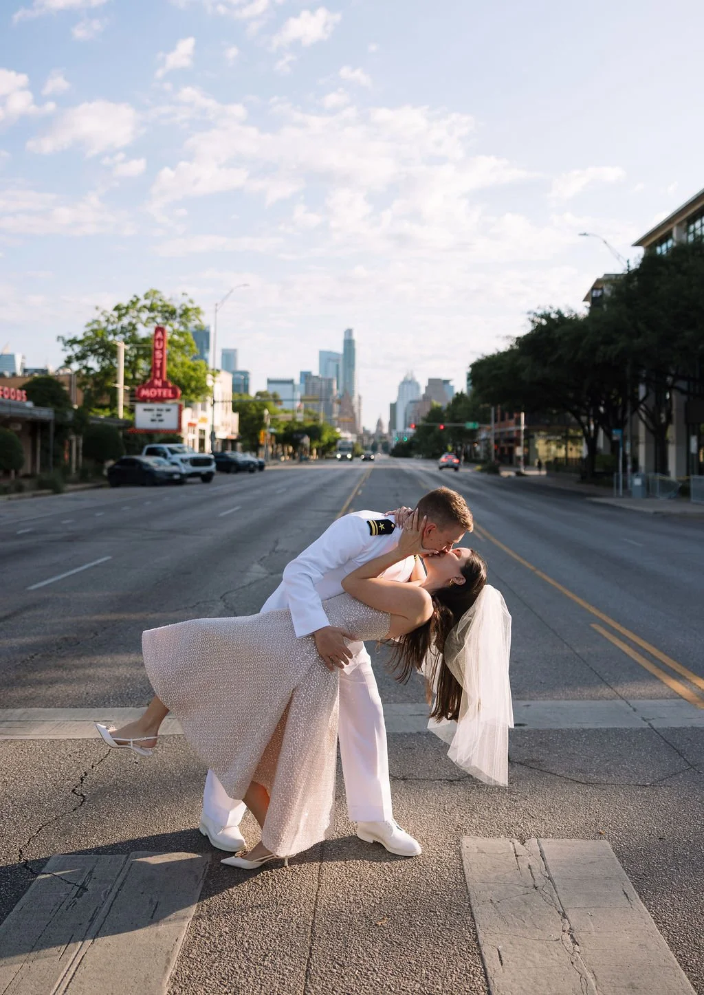 Mike dipping Stephanie for a kiss in the middle of South Congress street with city skyline view