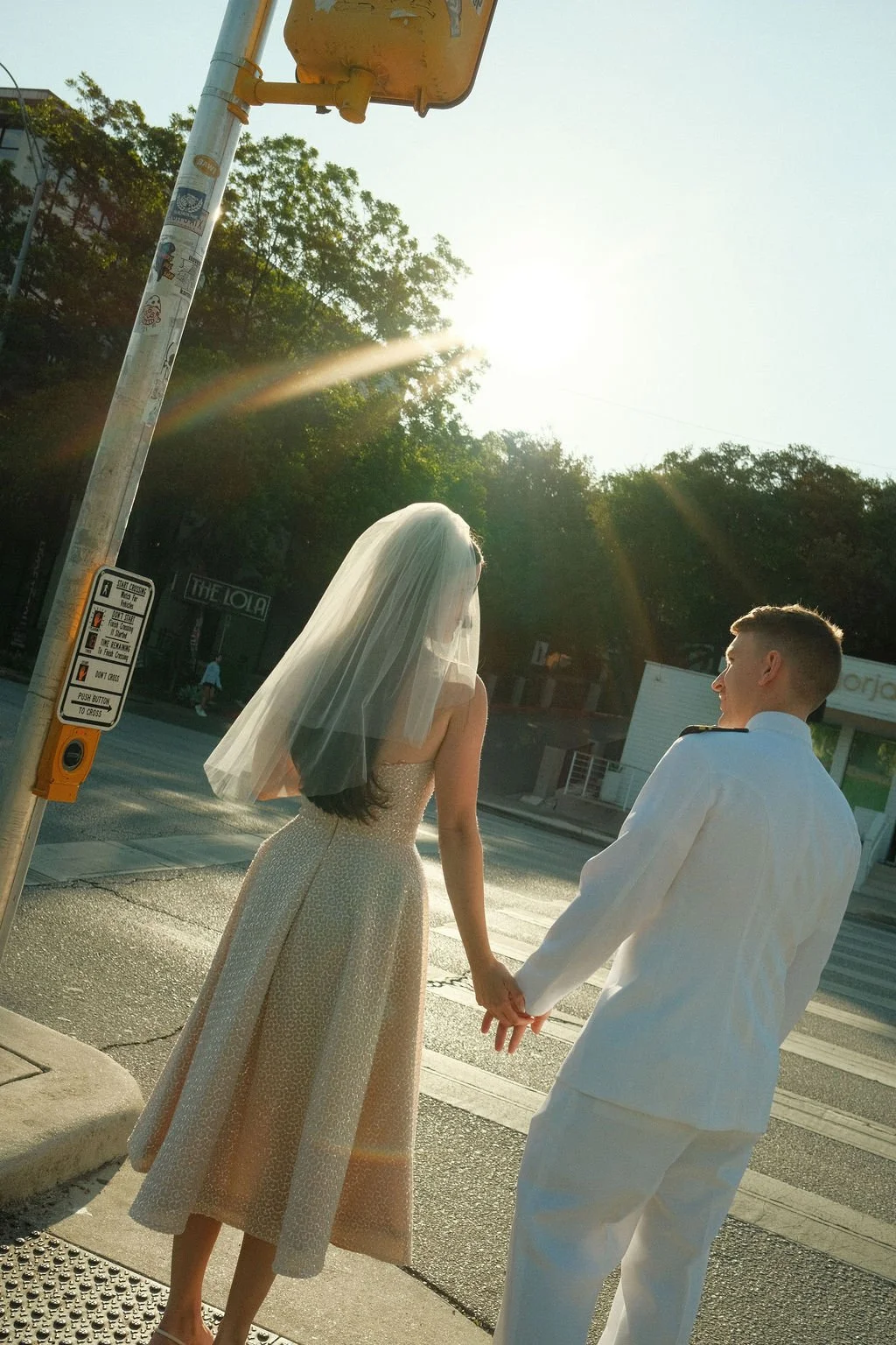 Stephanie and Mike holding hands at South Congress crosswalk with sunlight streaming in on fuji film