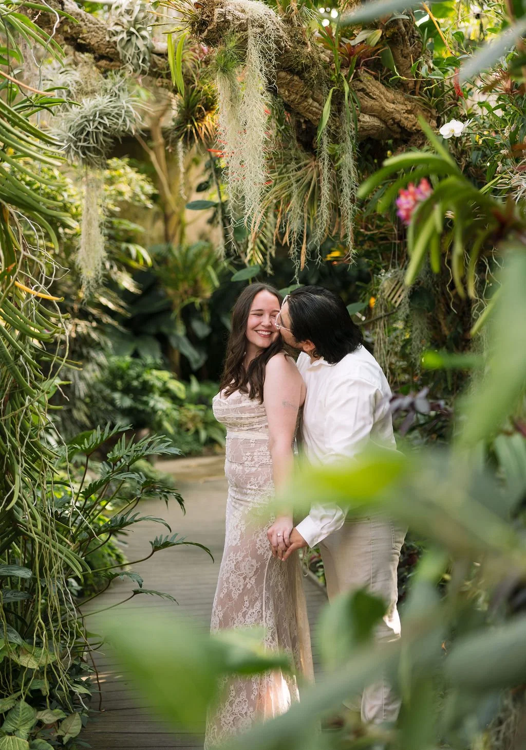 Couple embracing in tropical garden walkway during San Antonio engagement photos.