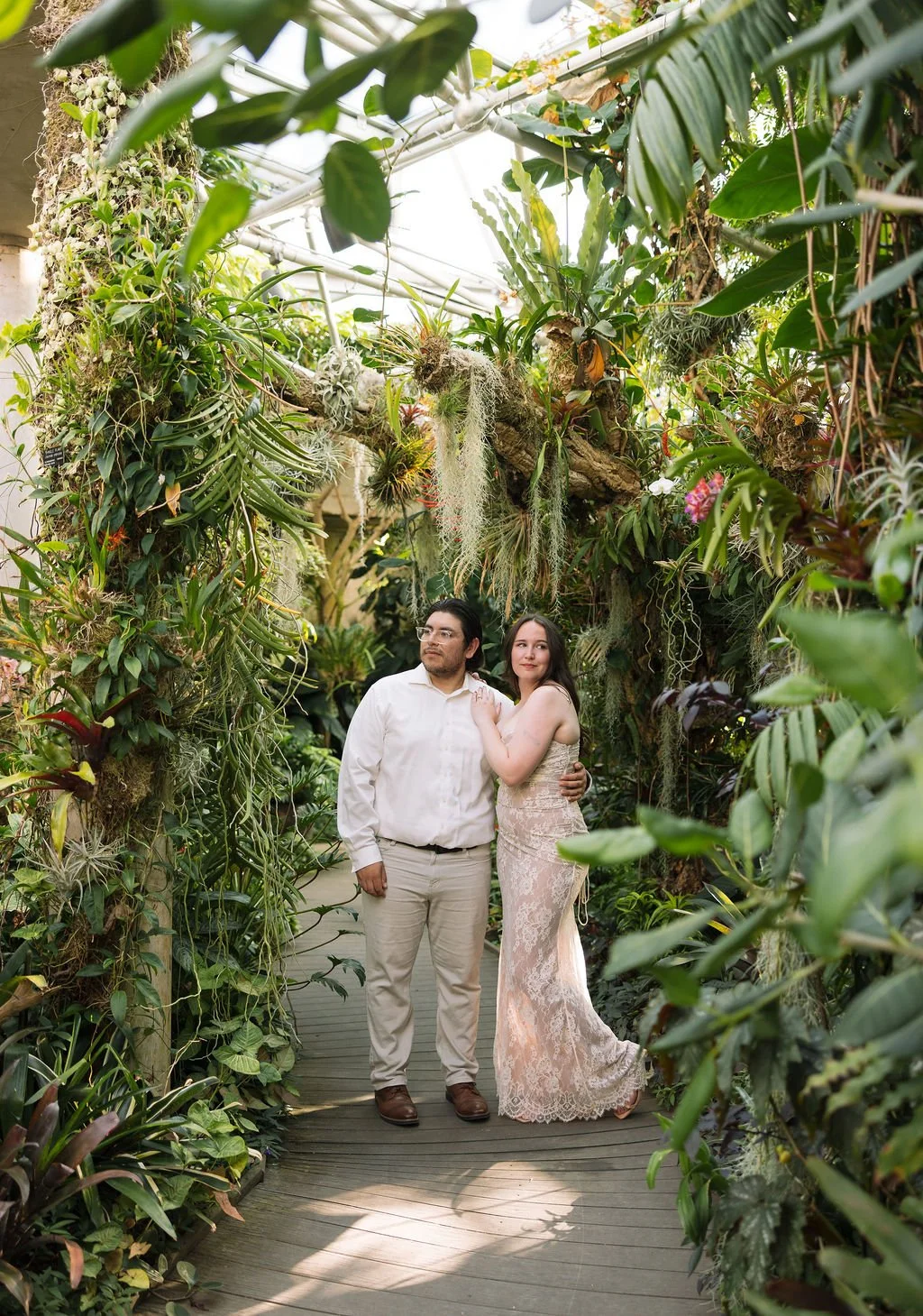 Couple walking together through lush plant-filled path at San Antonio Botanical Garden engagement session.
