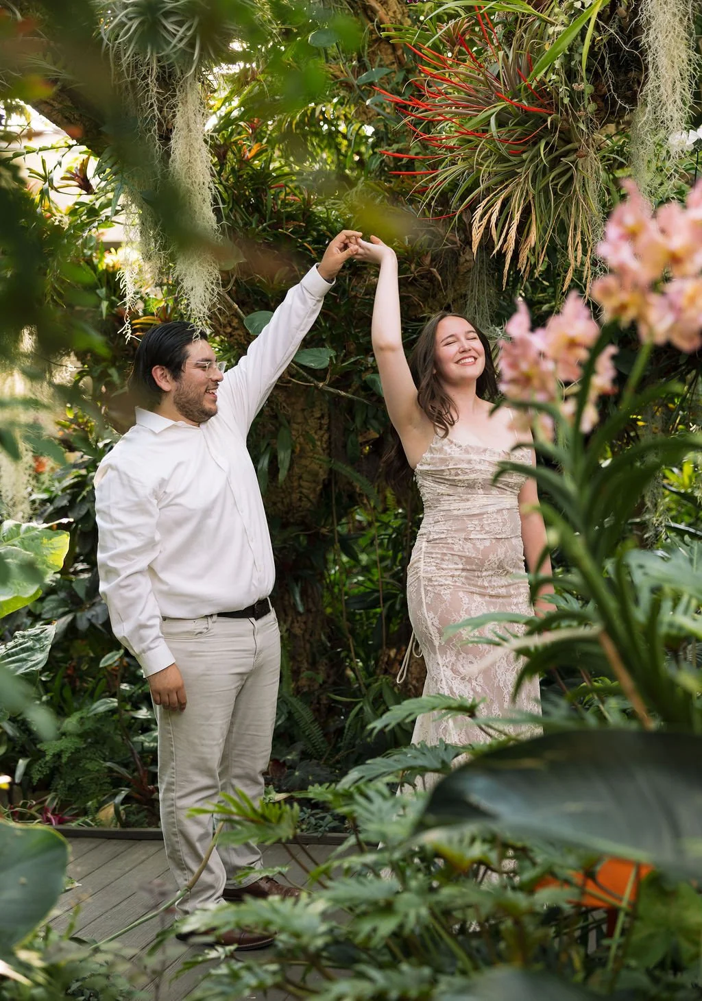 Couple walking together through lush plant-filled path at San Antonio Botanical Garden engagement session.