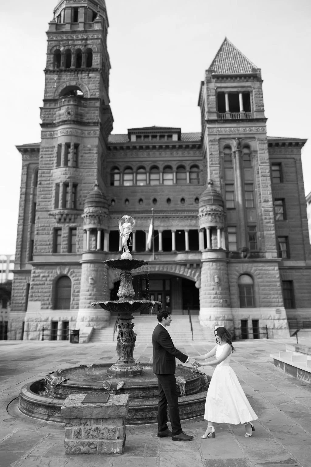 Couple twirling in black and white in front of Bexar County Courthouse San Antonio engagement session.