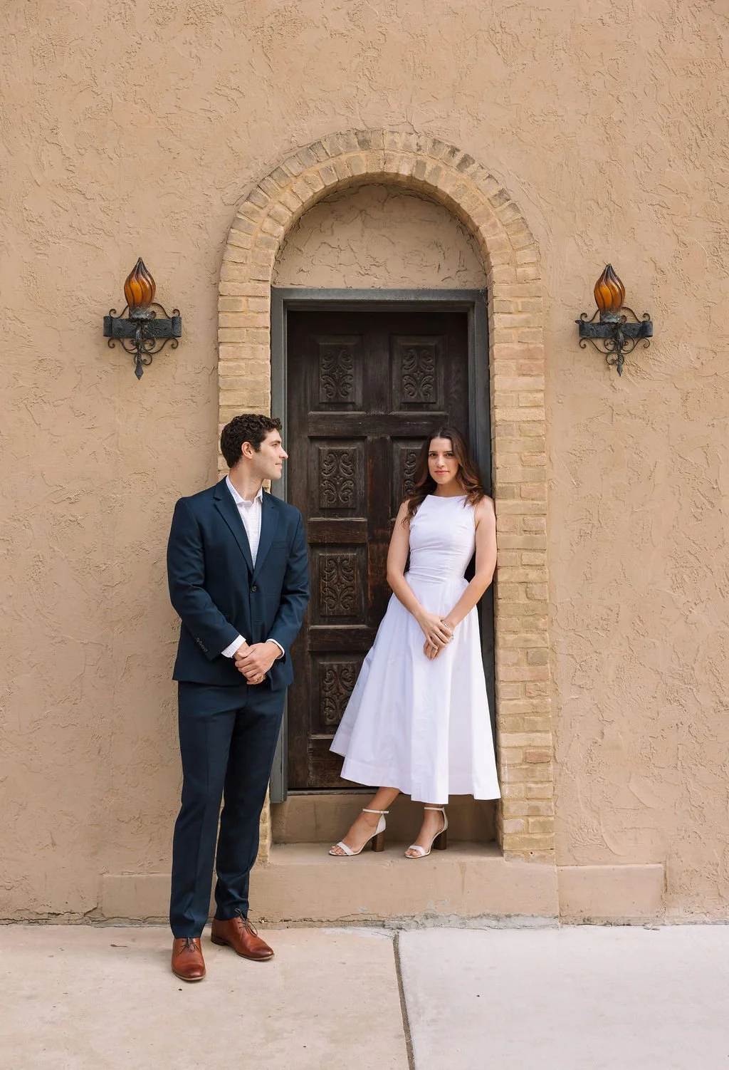Couple leaning against historic arched doorway downtown during San Antonio engagement session.