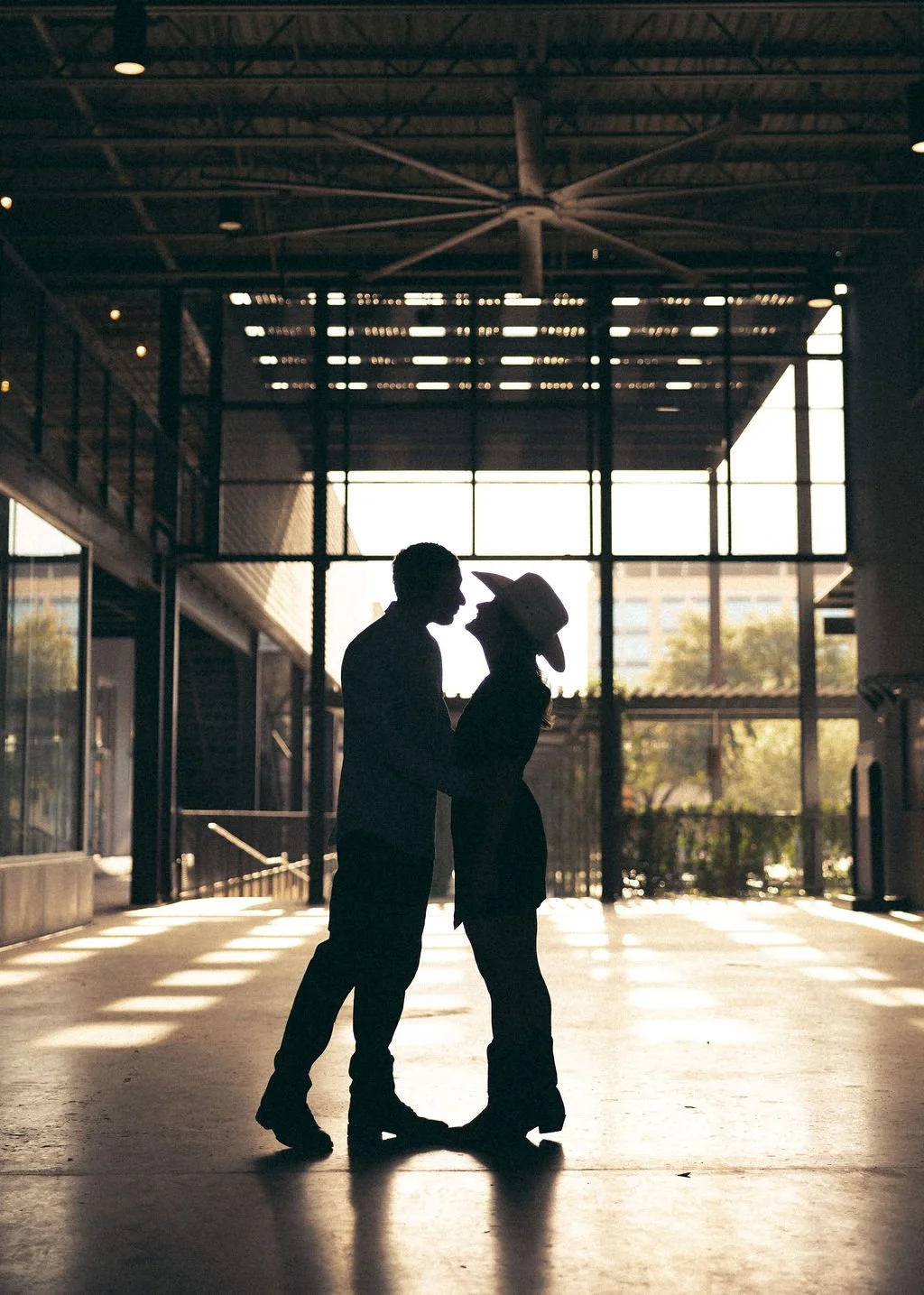 Couple trading cowboy hats in the Pearl lobby for moody light-and-shadow type of engagement phtoos