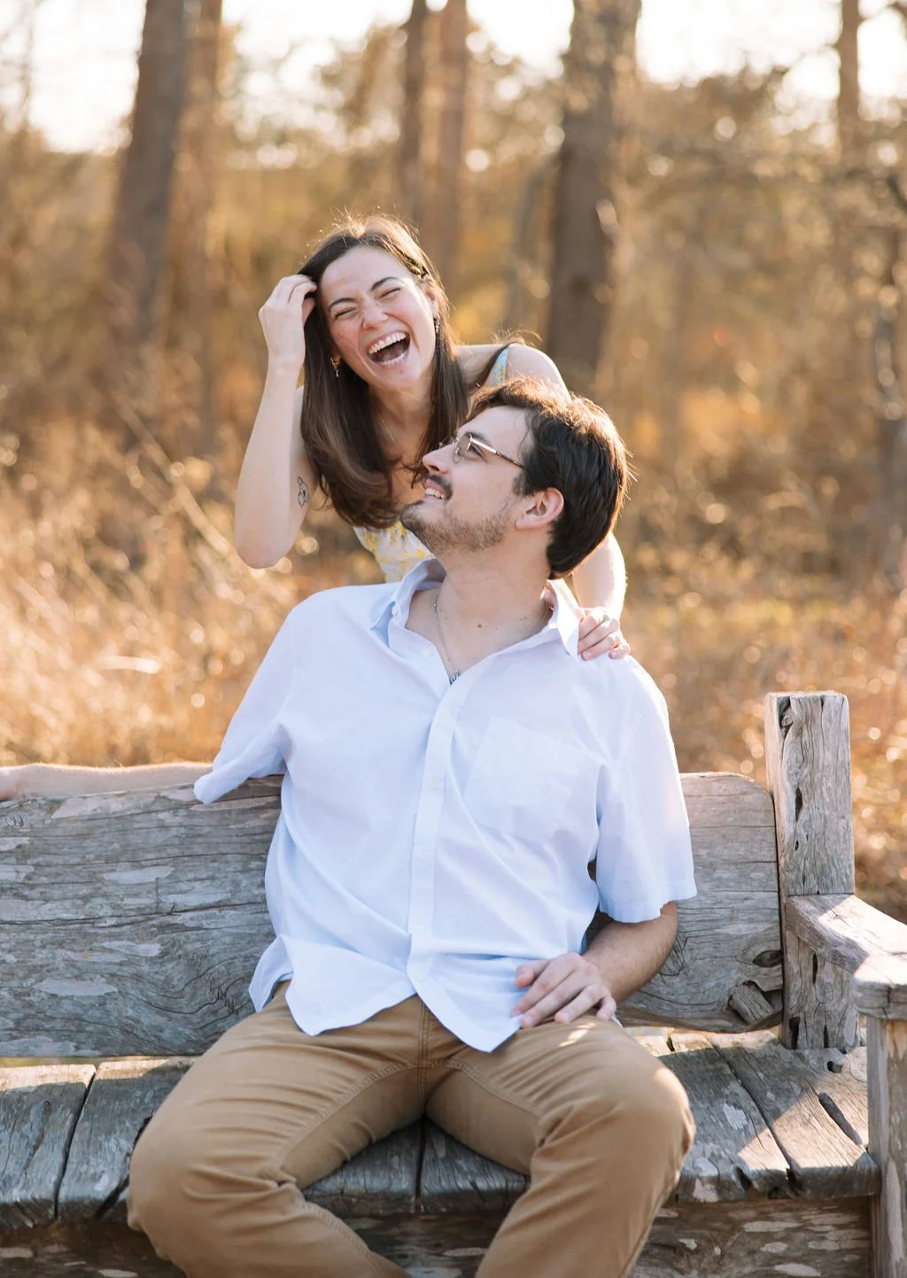Couple sitting close together on log surrounded by trees during San Antonio engagement session.