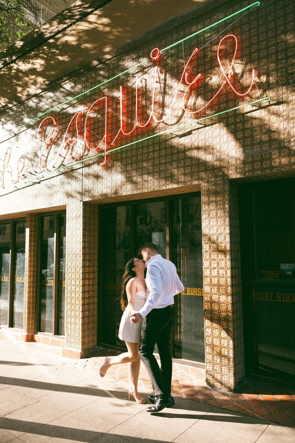Couple kissing under the neon "Esquire" sign, the oldest tavern in San Antonio