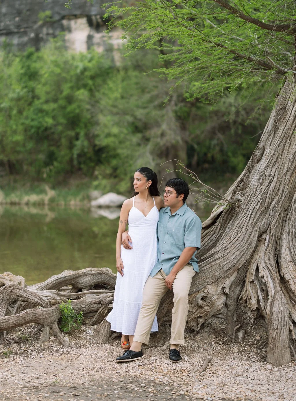 Couple standing by tree roots along riverbank during Guadalupe River State Park engagement photos San Antonio.