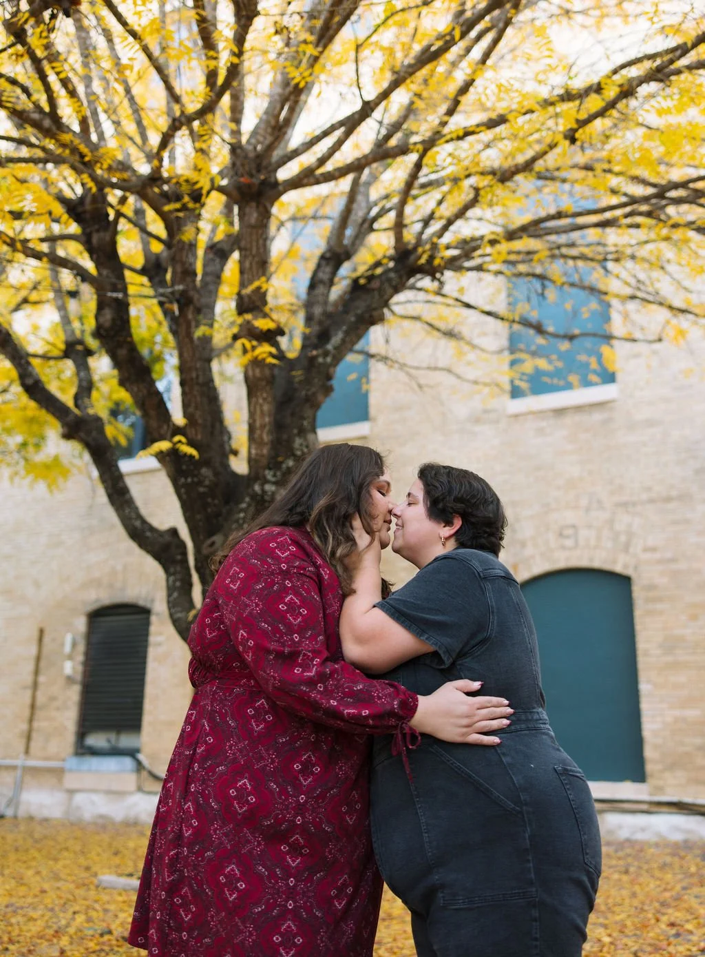 Couple kissing under autumn tree during San Antonio engagement photos at San Antonio Museum of Art.