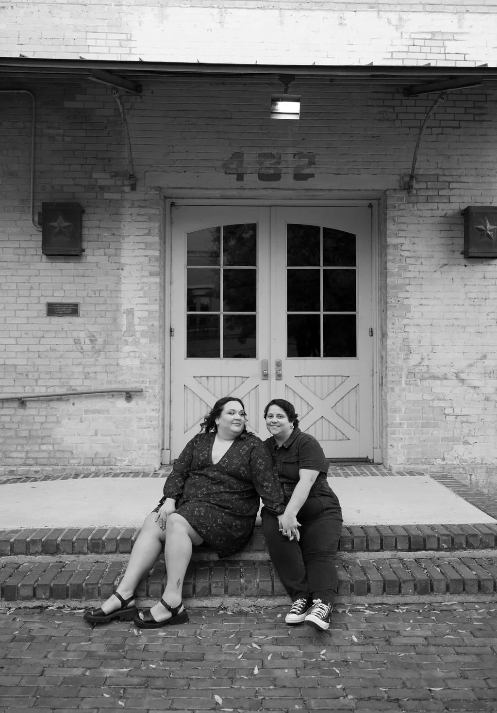 Couple sitting on stone steps in black and white during San Antonio engagement session at museum.