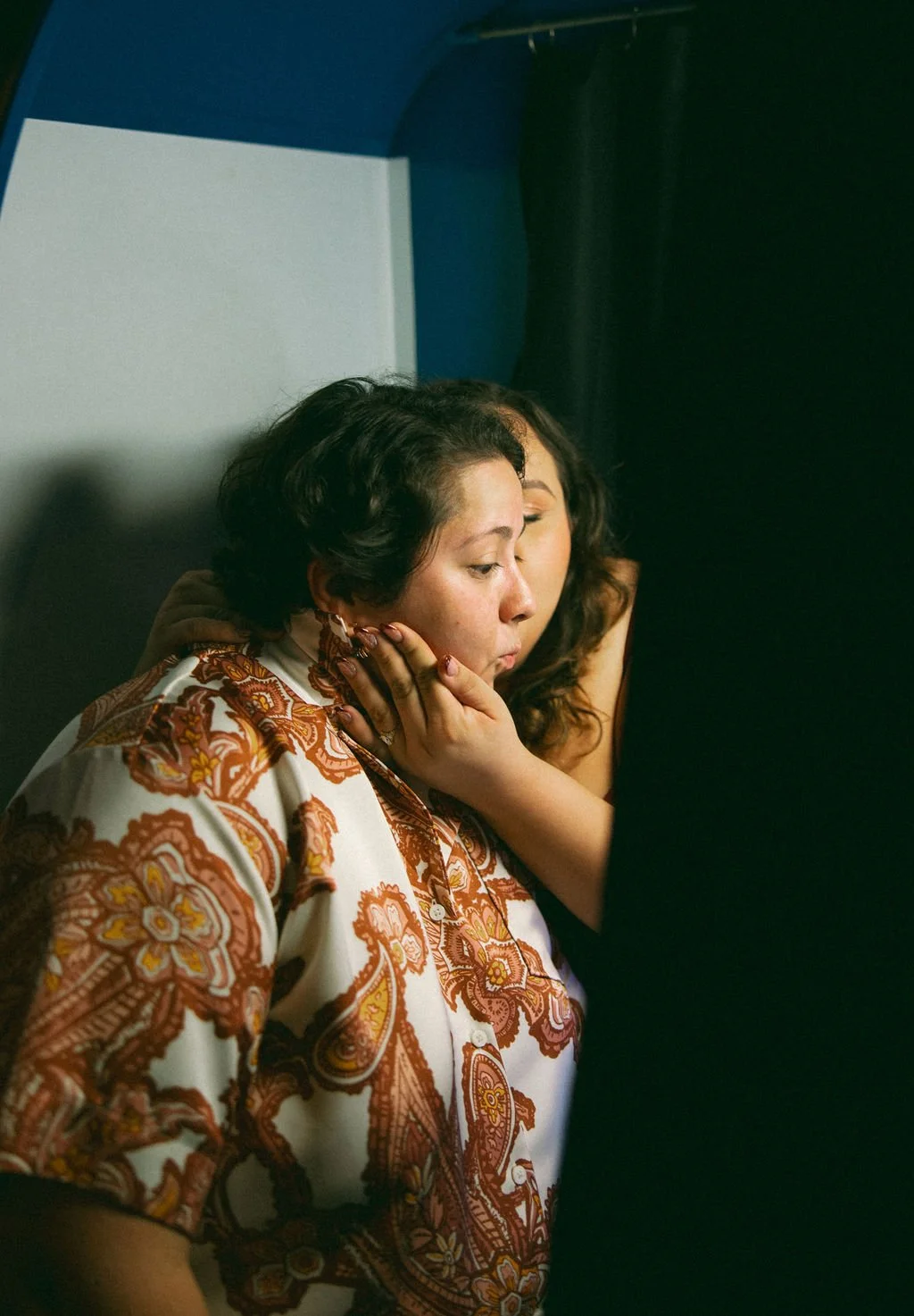 Close-up of couple cuddling in warm light while taking photobooth photos at Idle Beer Hall.