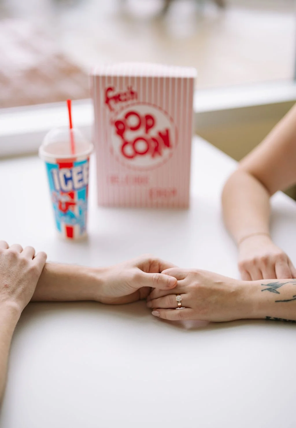 Close-up of couple holding hands across diner table during San Antonio engagement photos at Stars &amp; Stripes.
