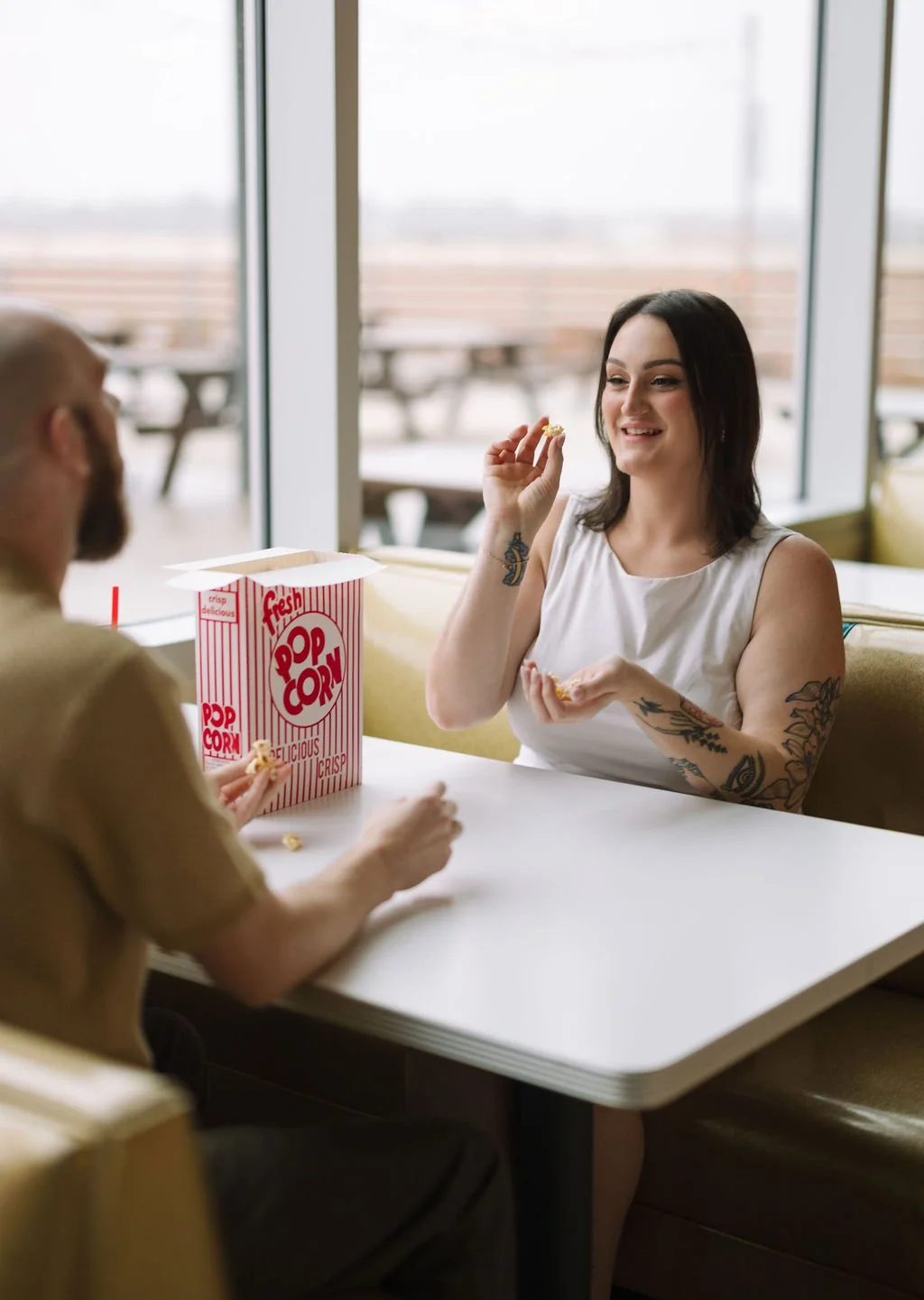 Couple laughing together at diner booth during Stars &amp; Stripes Drive-In engagement photos San Antonio.