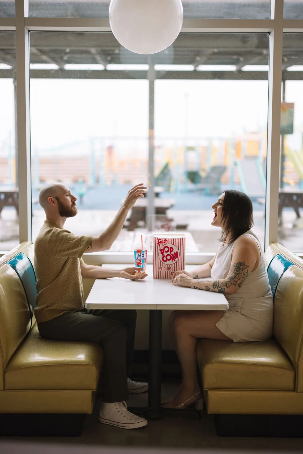 Couple playing with popcorn in black and white during San Antonio engagement photos at retro drive-in.