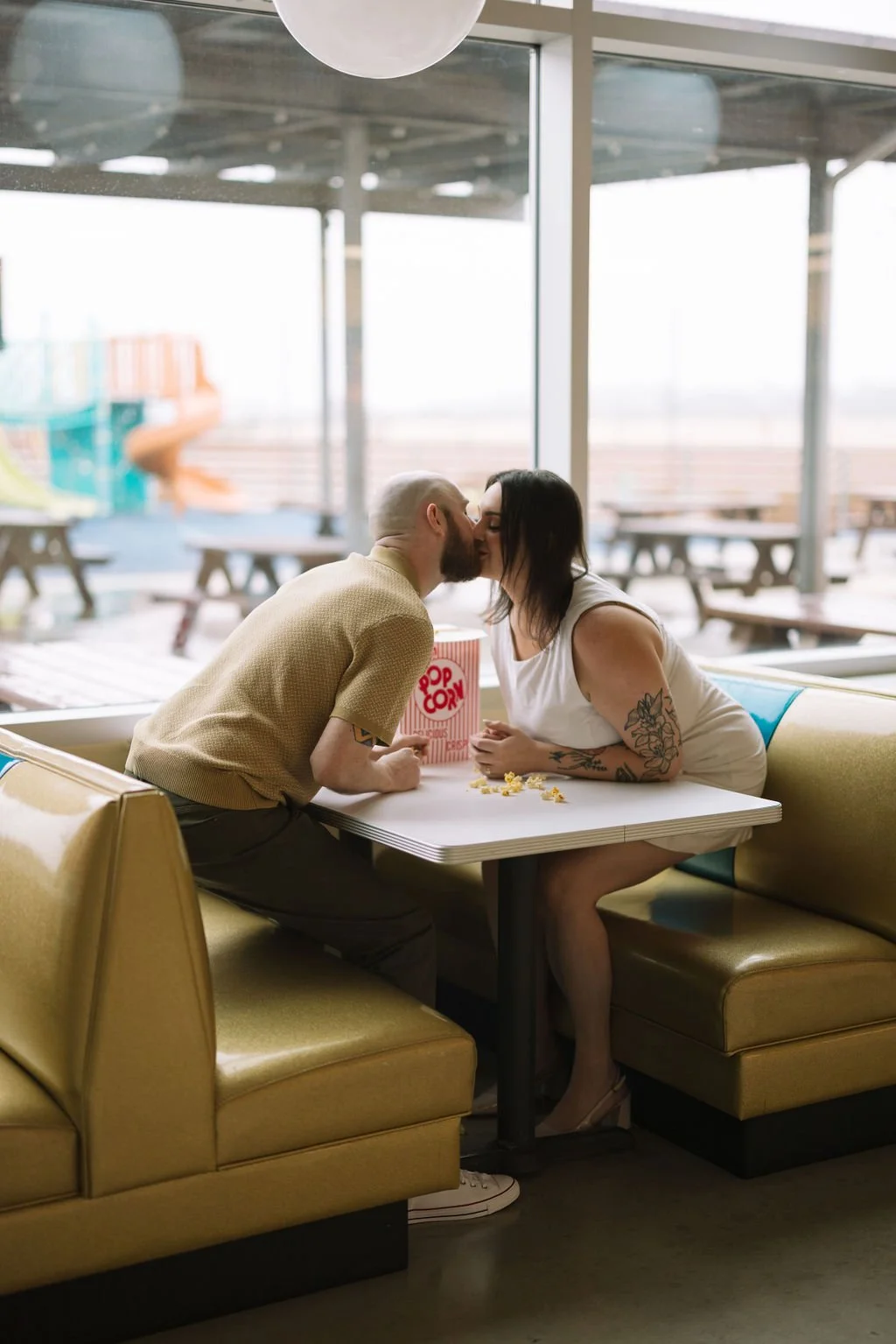 Couple kissing across diner table during Stars &amp; Stripes Drive-In engagement session in San Antonio.