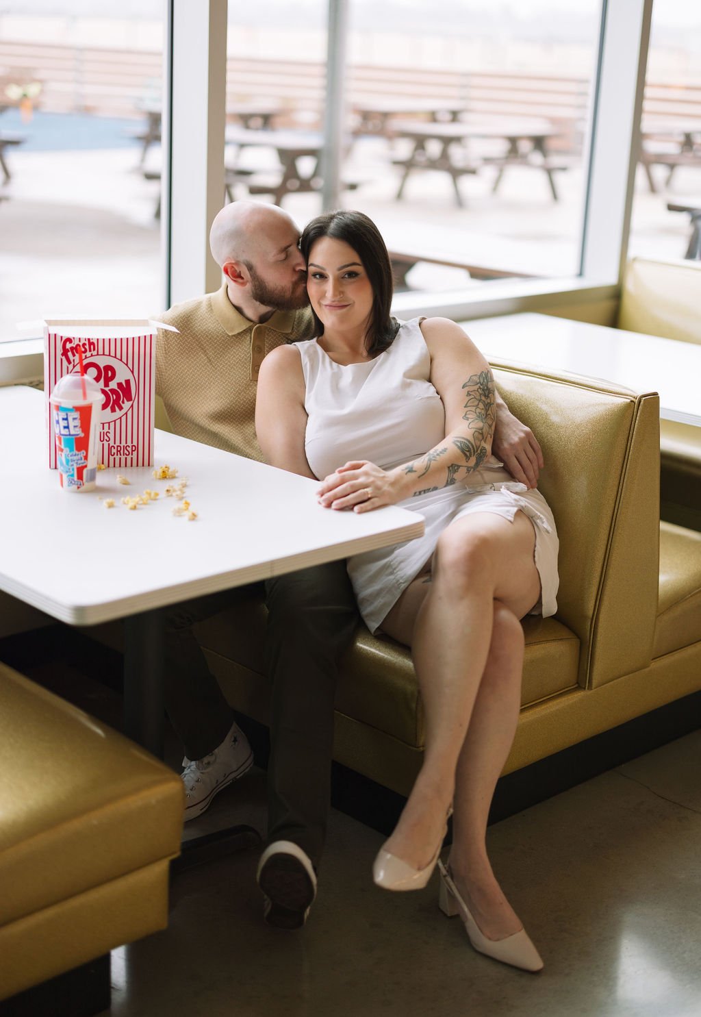 Couple snuggling together at retro booth during San Antonio engagement photos at Stars &amp; Stripes Drive-In.
