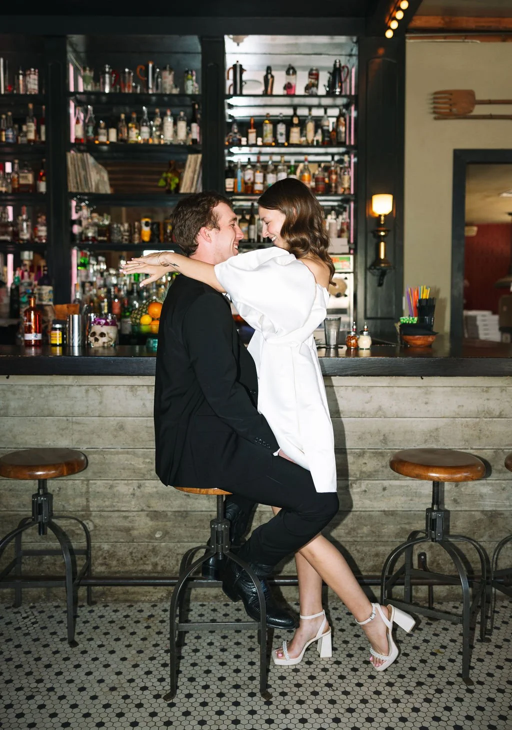Couple embracing at bar counter during San Antonio engagement photos at Barbaro.