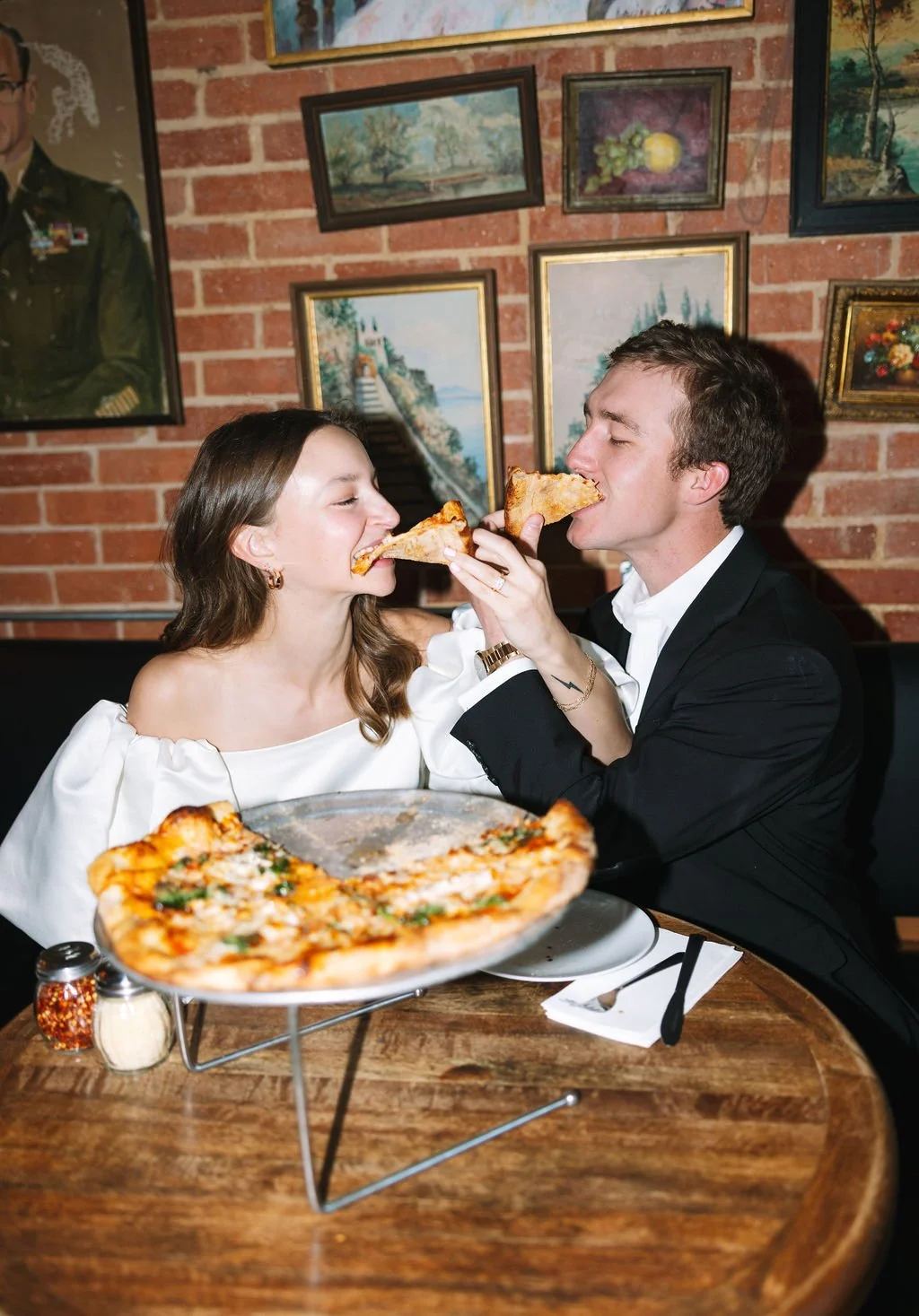 Couple sharing a piece of pizza in a speakeasy bar restaurant setting for the San Antonio engagement photos