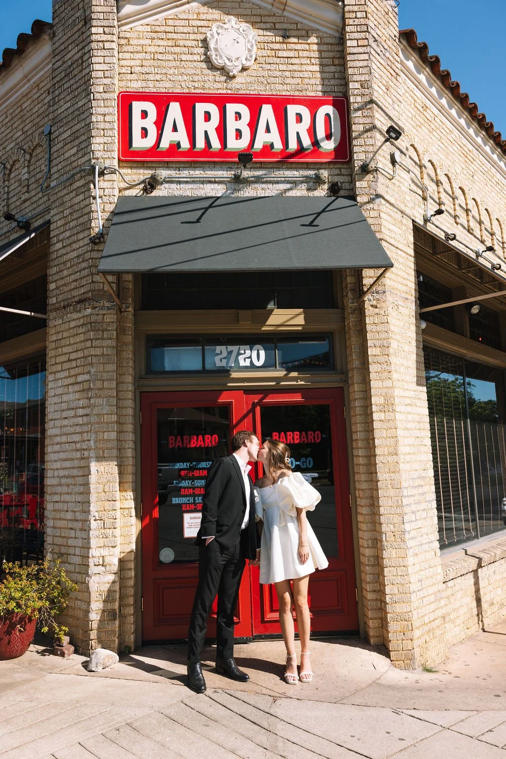 Couple kissing in front of Barbaro Italian Restaurant for their San Antonio engagement photos.