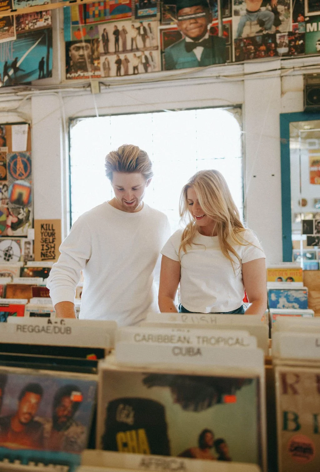 Couple browsing vinyl records together inside Friends of Sound during San Antonio engagement session.
