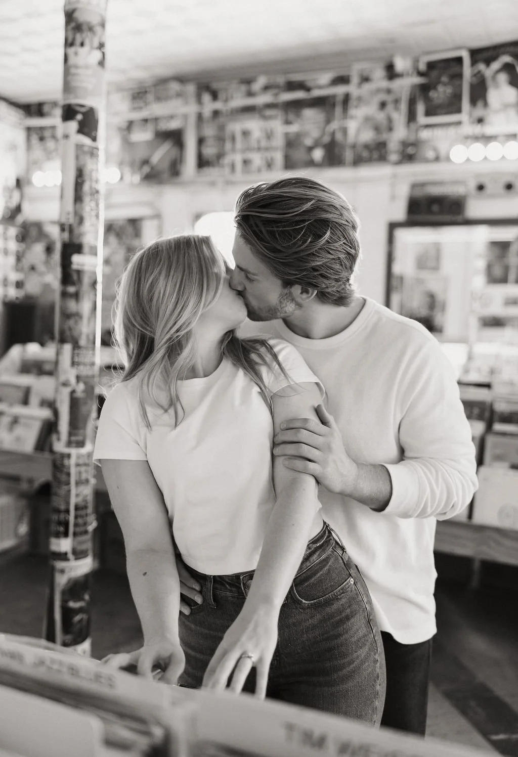 Couple kissing in black and white while looking at records during Friends of Sound engagement photos.