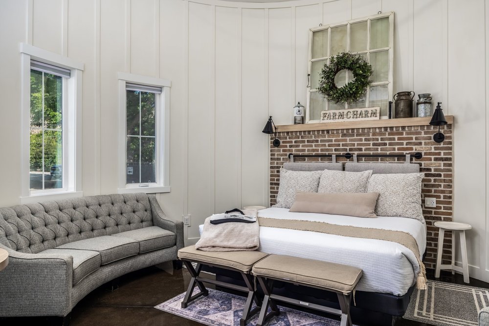 Guest suite with a brick accent wall, bed and upholstered sofa at The Silo Suites